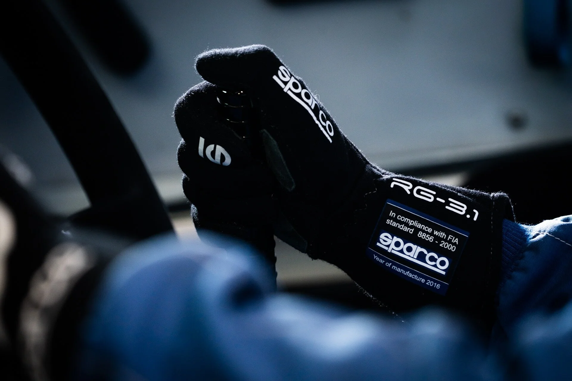 A close-up of a driver’s gloved hand holding a lever inside the cockpit of a rally car.
