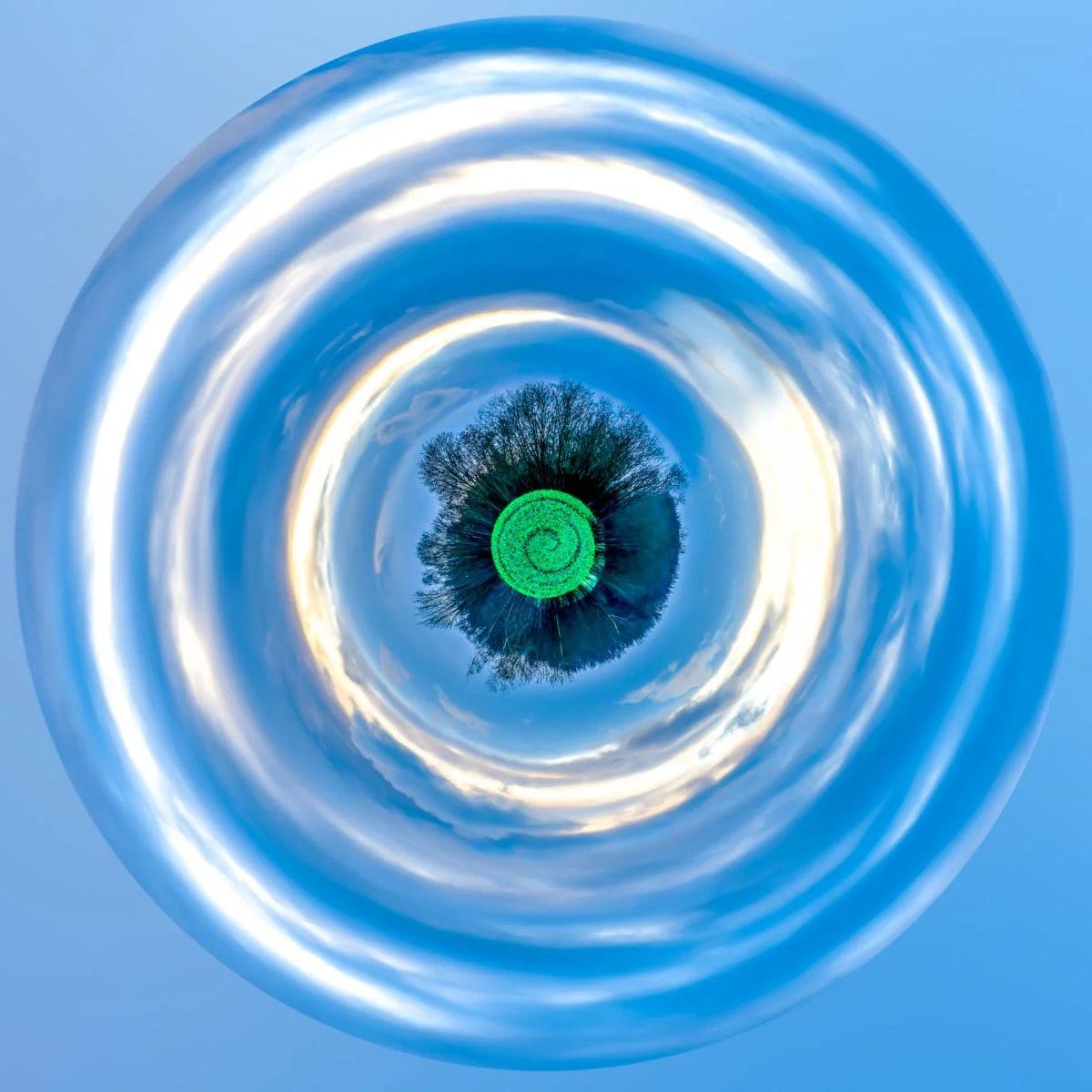 A small, green planet at the centre of rings of white clouds against a blue sky.
