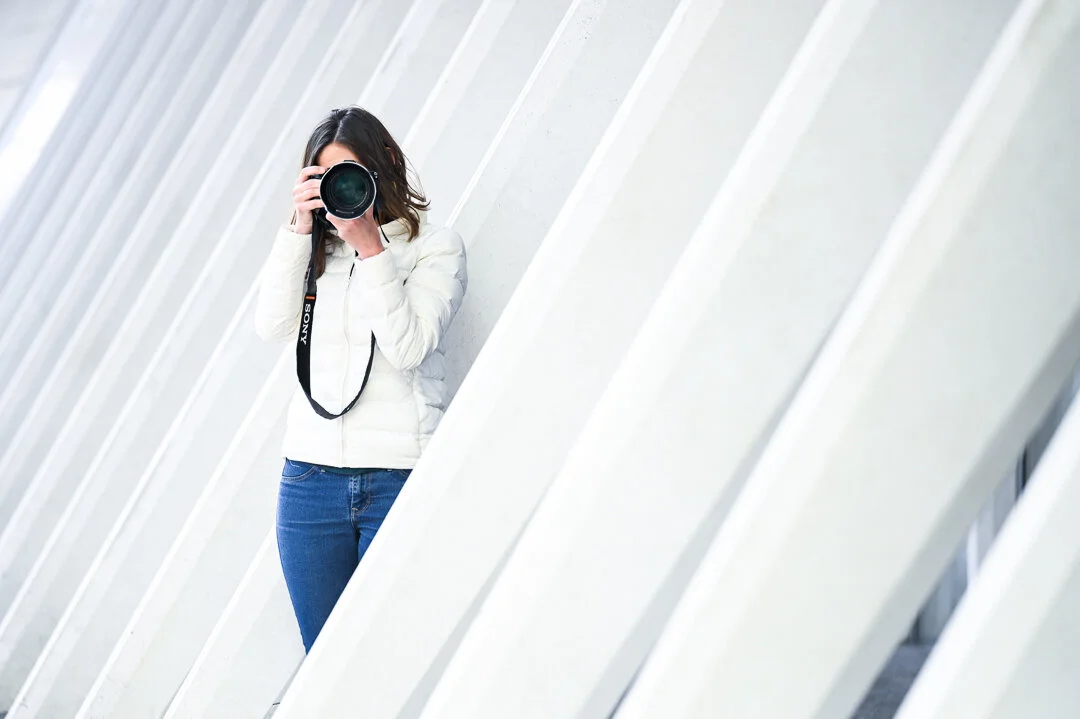 A photographer takes a photo amongst large, sloping white structures.