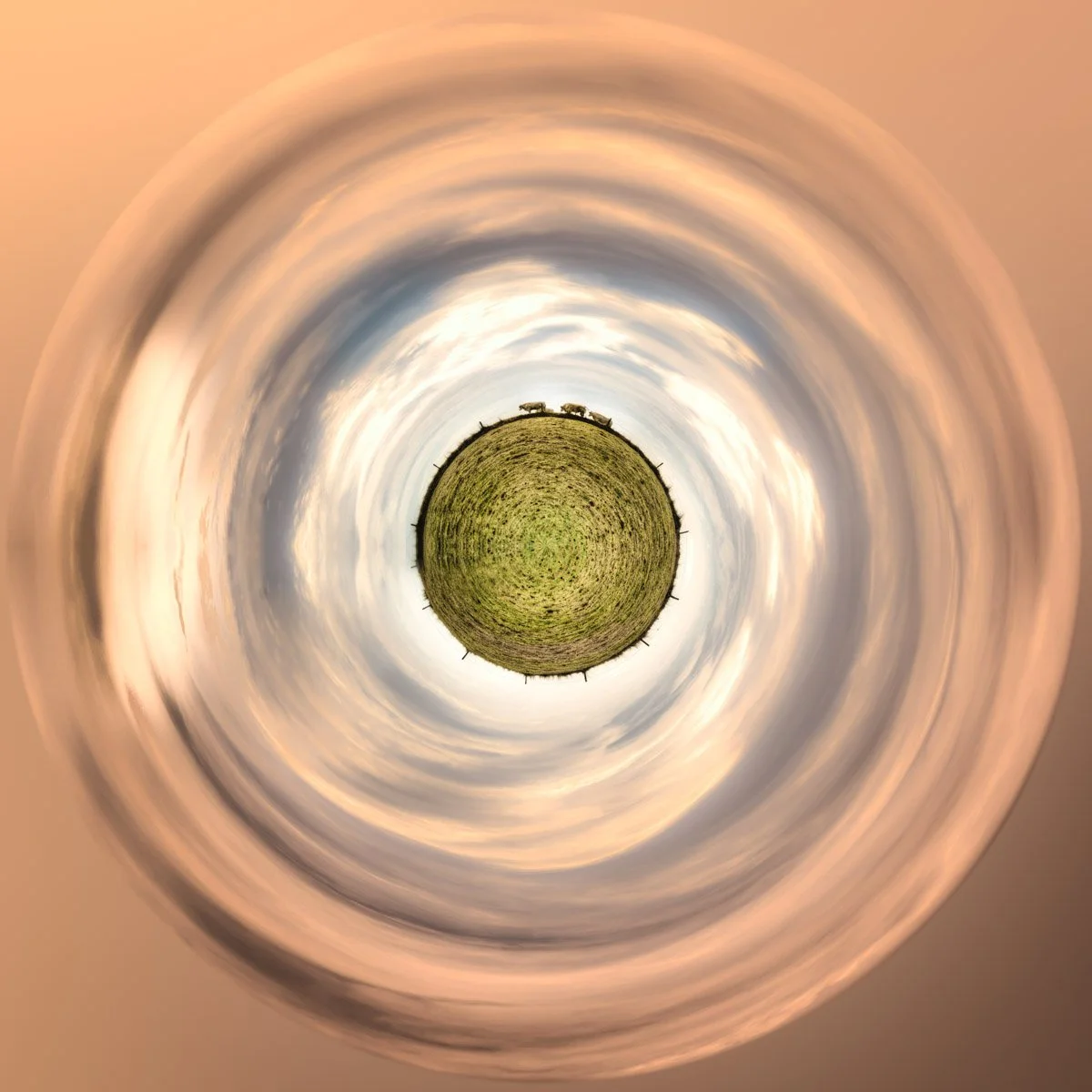 A small, plant-covered planet surrounded by rings of clouds in shades of grey and orange.