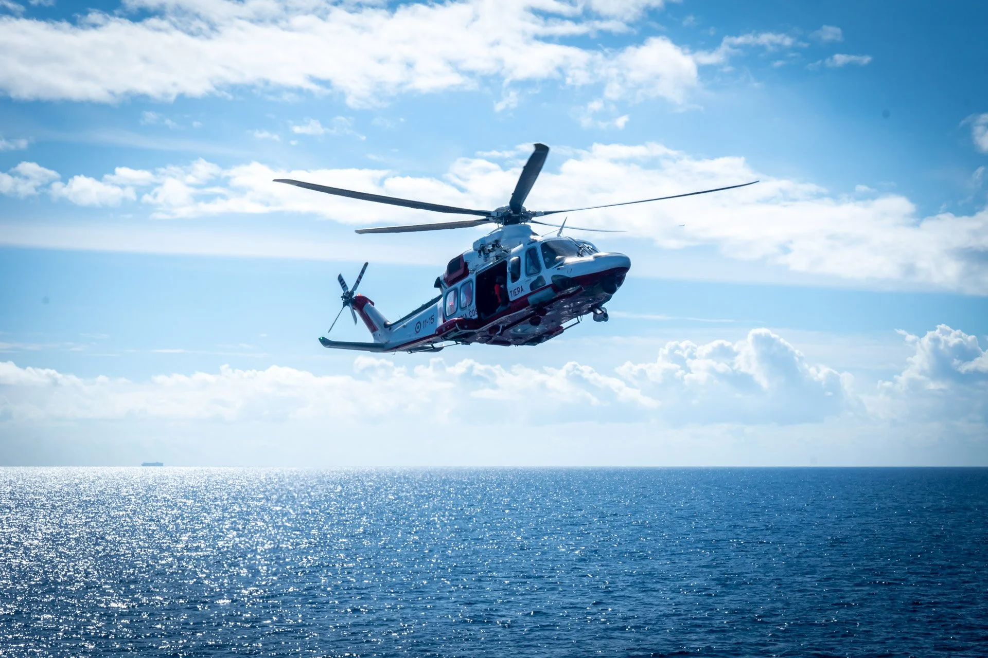 Un hélicoptère volant au-dessus de la mer avec un ciel bleu en arrière-plan.