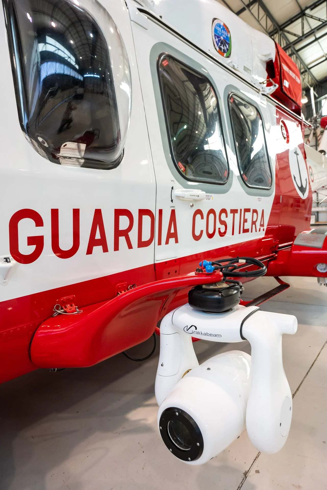 Hélicoptère de la Guardia Costiera avec équipement spécifique attaché, intérieur d'un hangar.