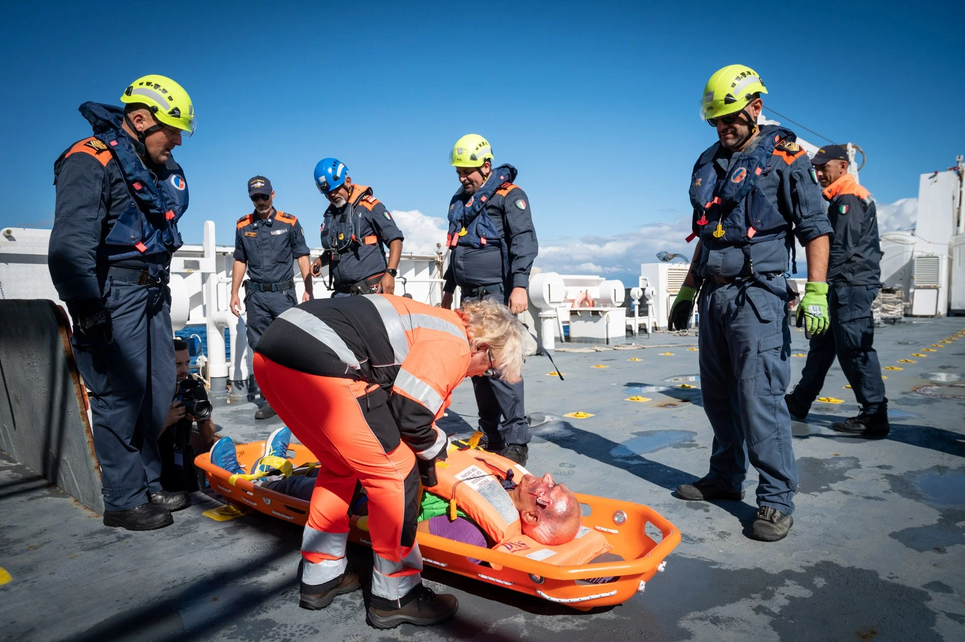 Équipe de secouristes sur un bateau, avec un mannequin sur un brancard pour un exercice de sauvetage en mer.