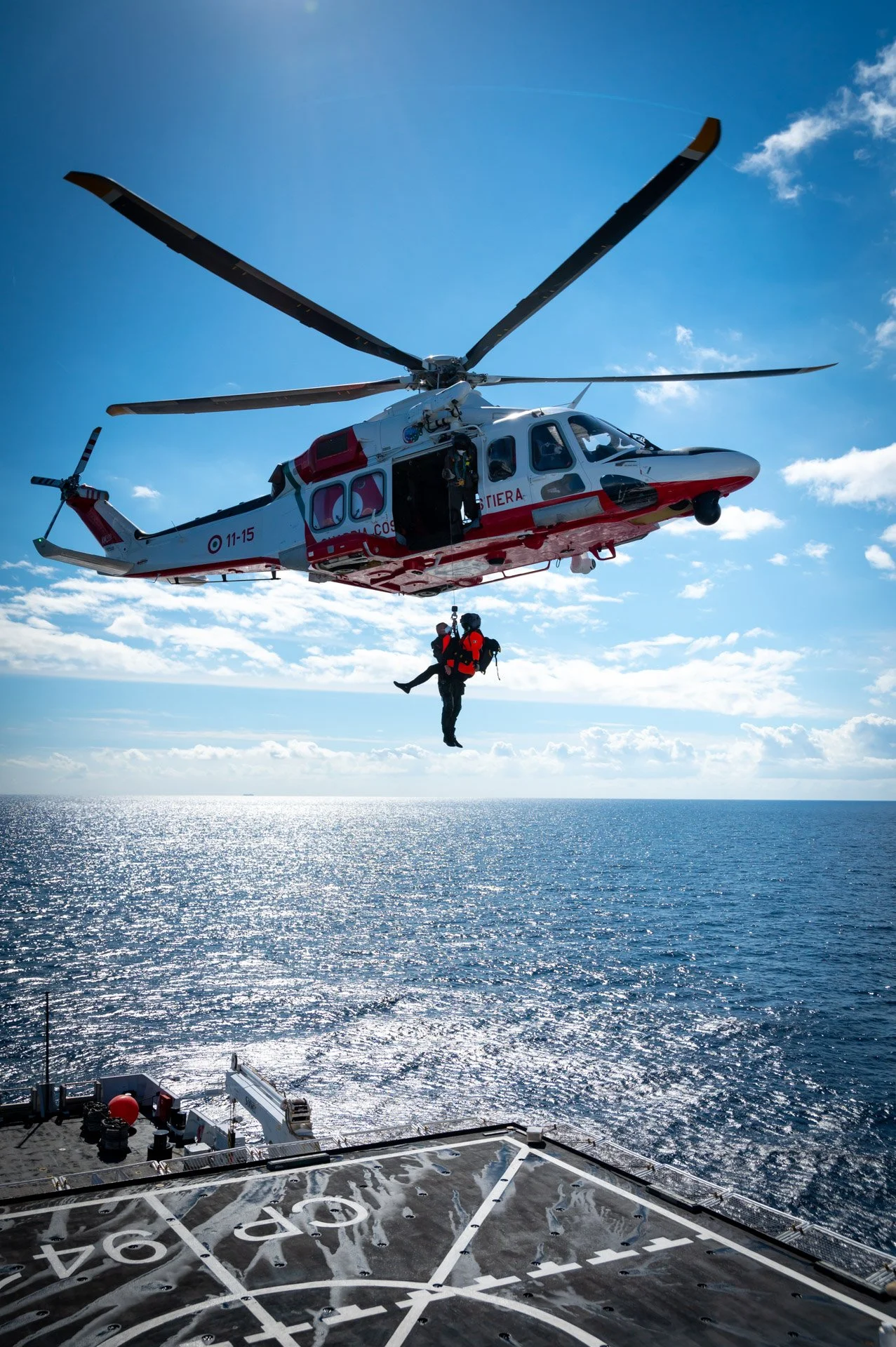 Hélicoptère de la garde côtière effectuant une opération de sauvetage en mer, vue depuis le pont d'un navire.