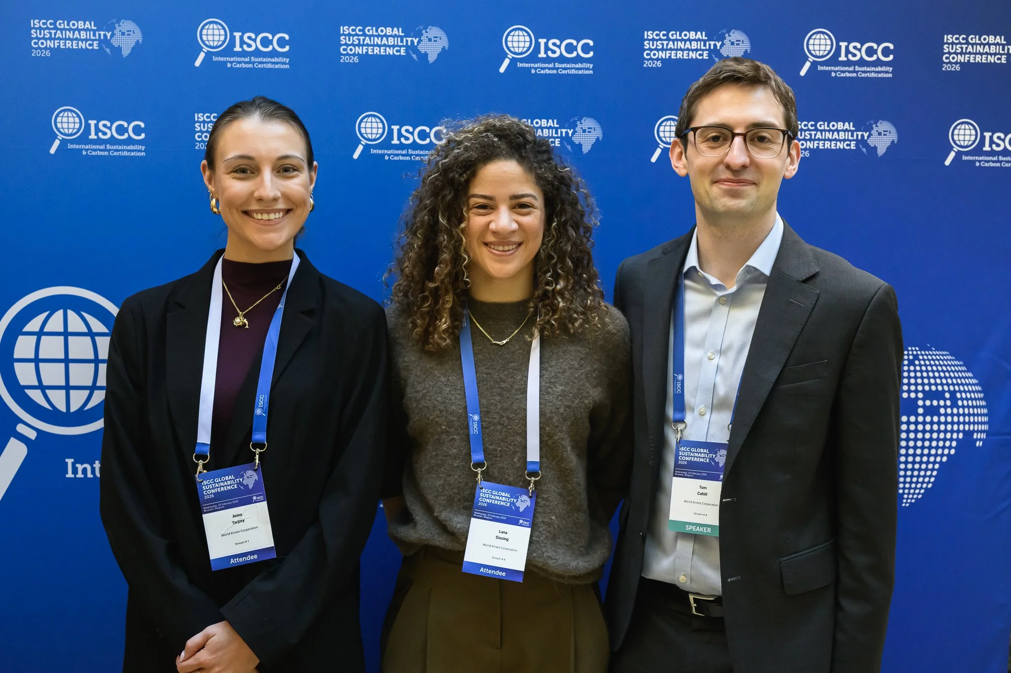 Two women and a man pose in front of a blue ISCC backdrop.