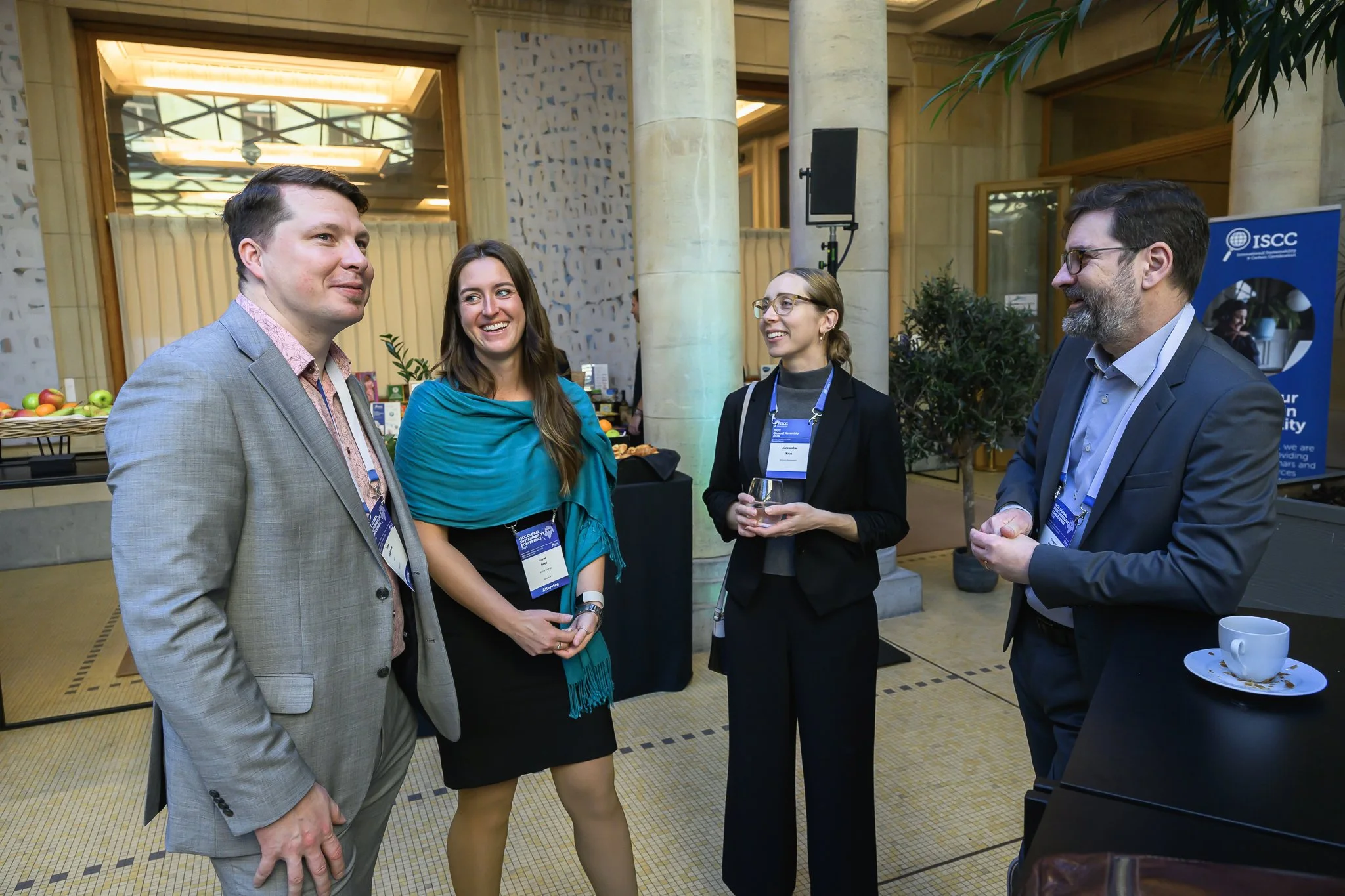 Four participants wearing lanyards converse in the conference lobby.