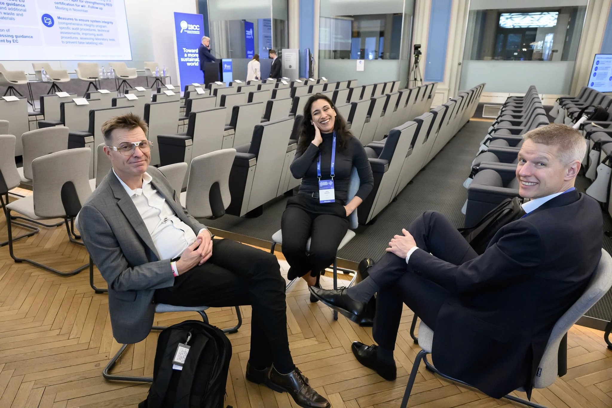 Three participants sit together and talk among rows of chairs in the auditorium.
