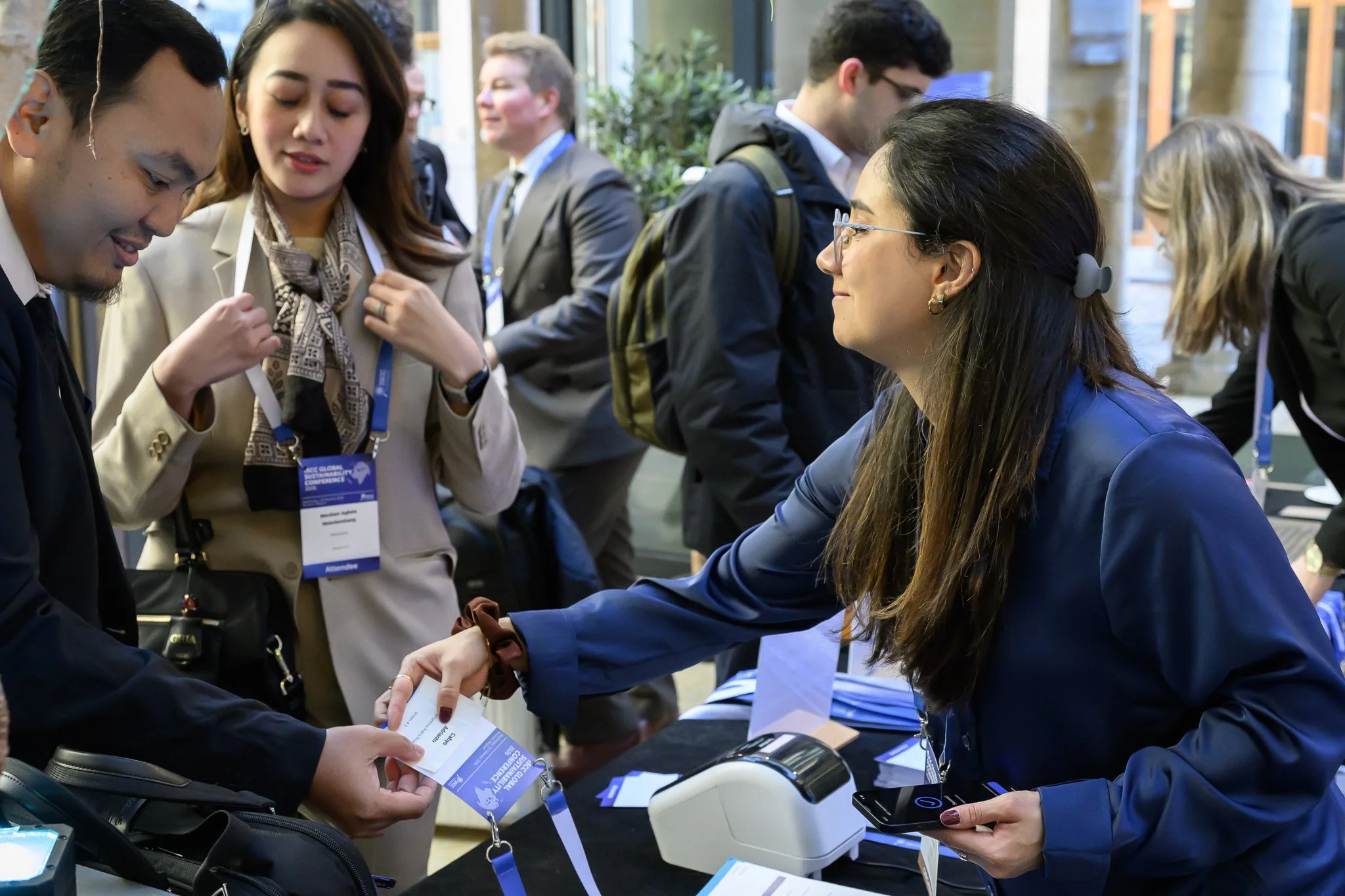 Conference staff hand registration materials to arriving participants.