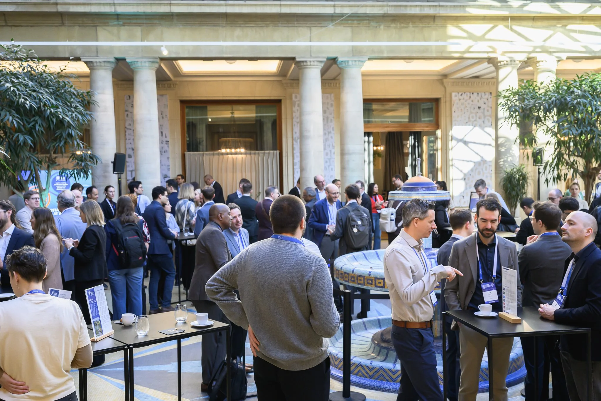 Participants mingle around tall tables in the conference reception area.