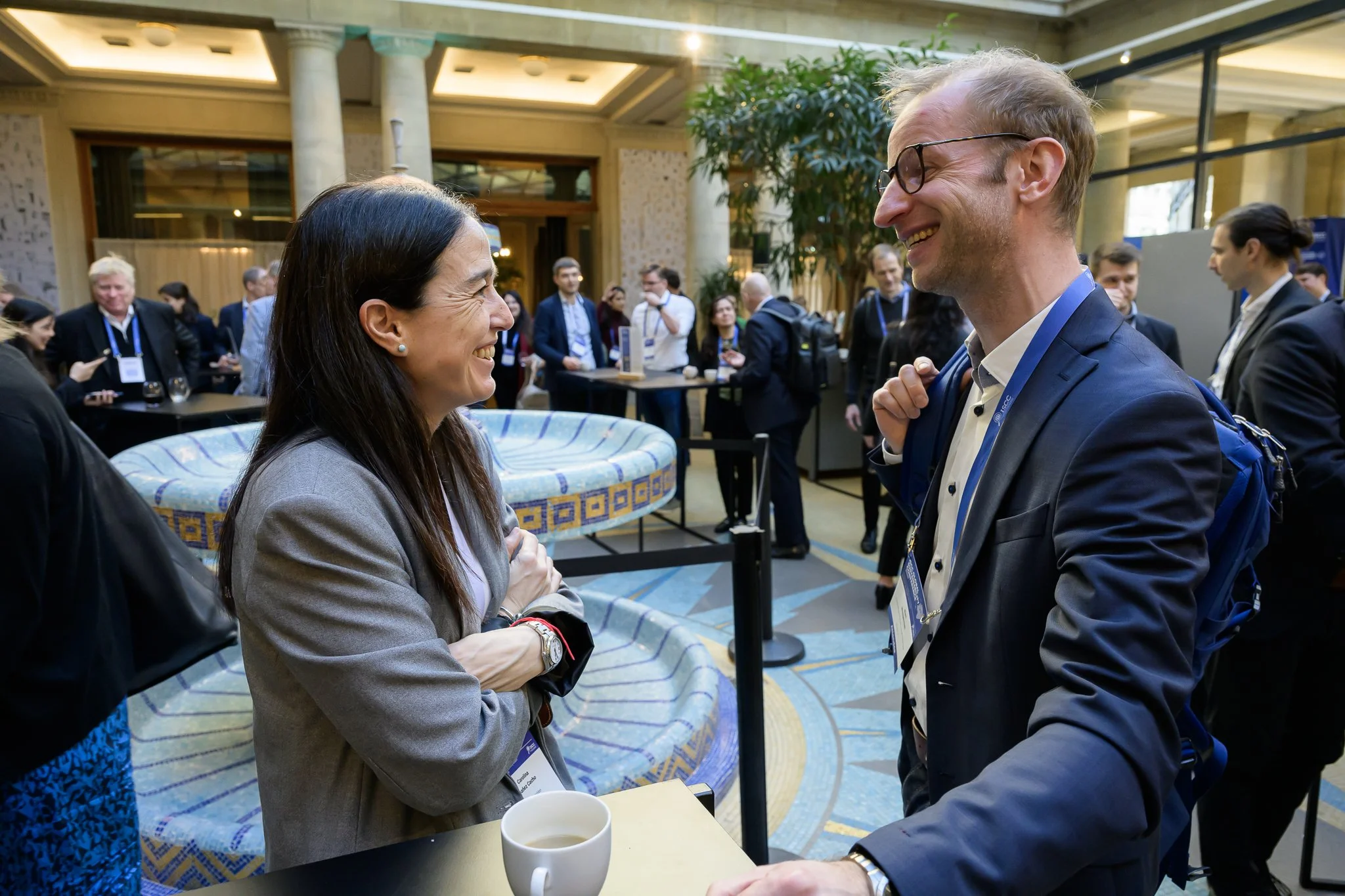 A woman and a man converse at a tall table in the conference lobby.