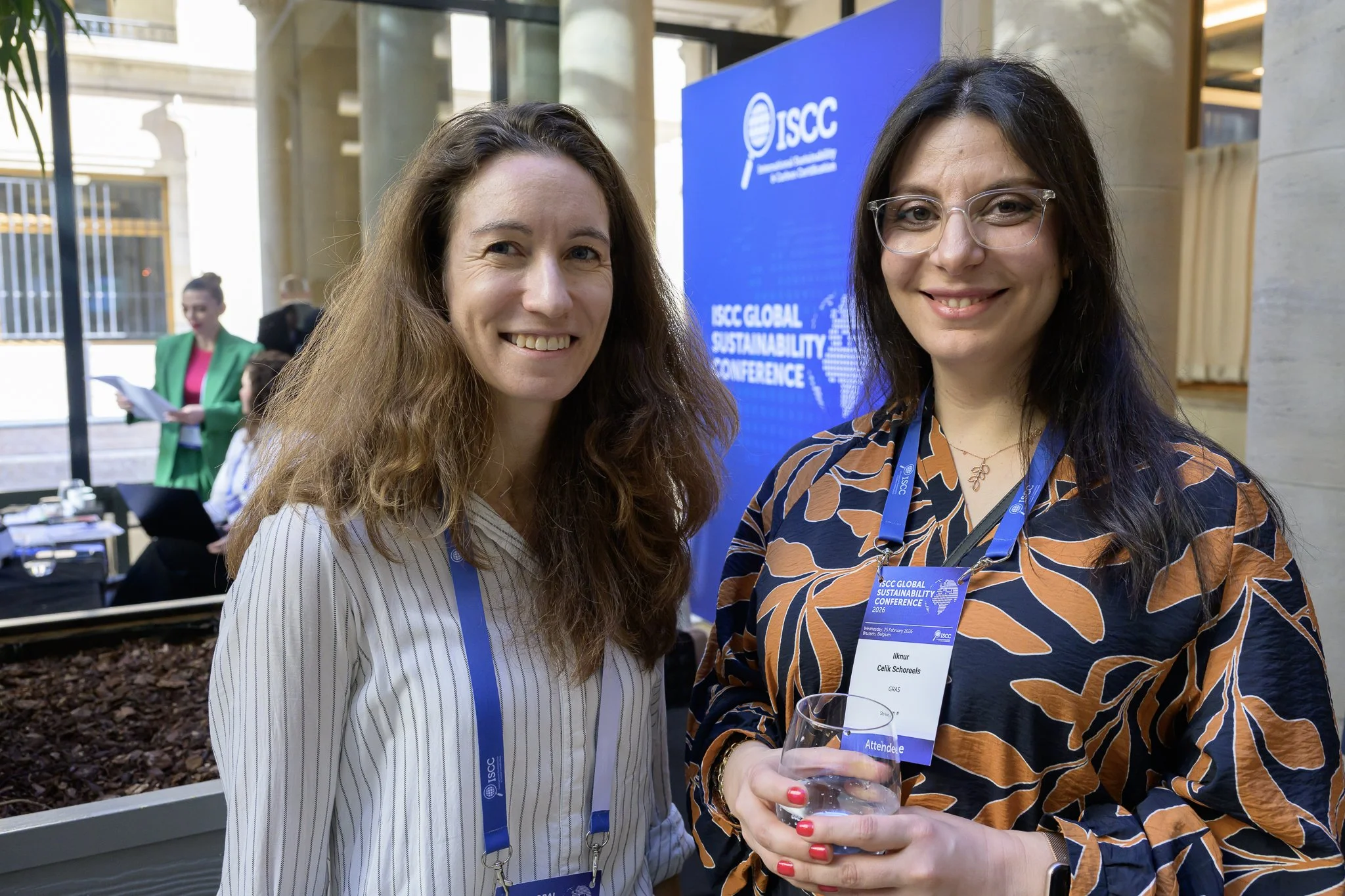 Two smiling women pose together near the conference registration area.