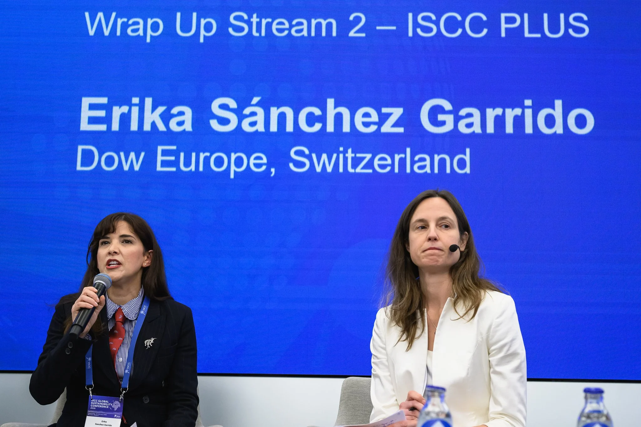 A woman speaks into a microphone beneath a slide naming Erika Sánchez Garrido.