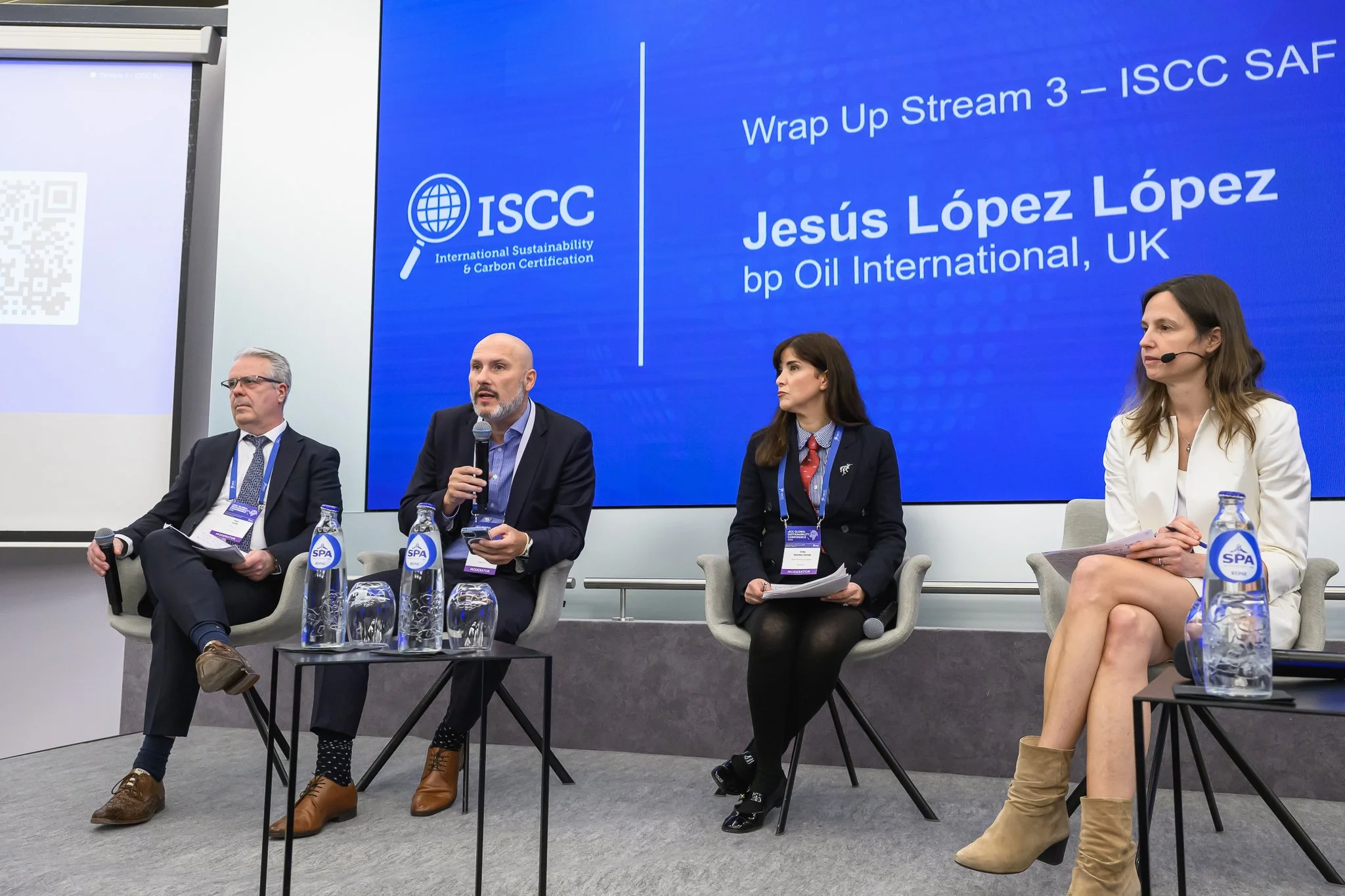 Four participants sit beneath a slide summarising the ISCC SAF conference stream.