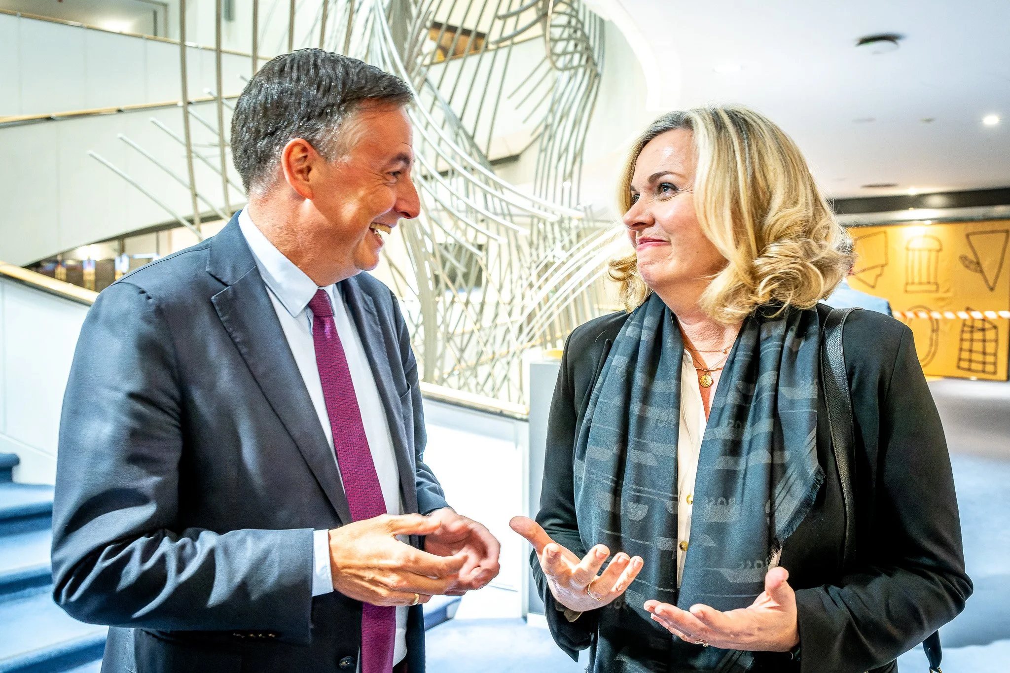 Photo professionnelle d'un cocktail au Parlement européen qui montre deux personnes discutant dans un environnement professionnel, décor moderne en arrière-plan.