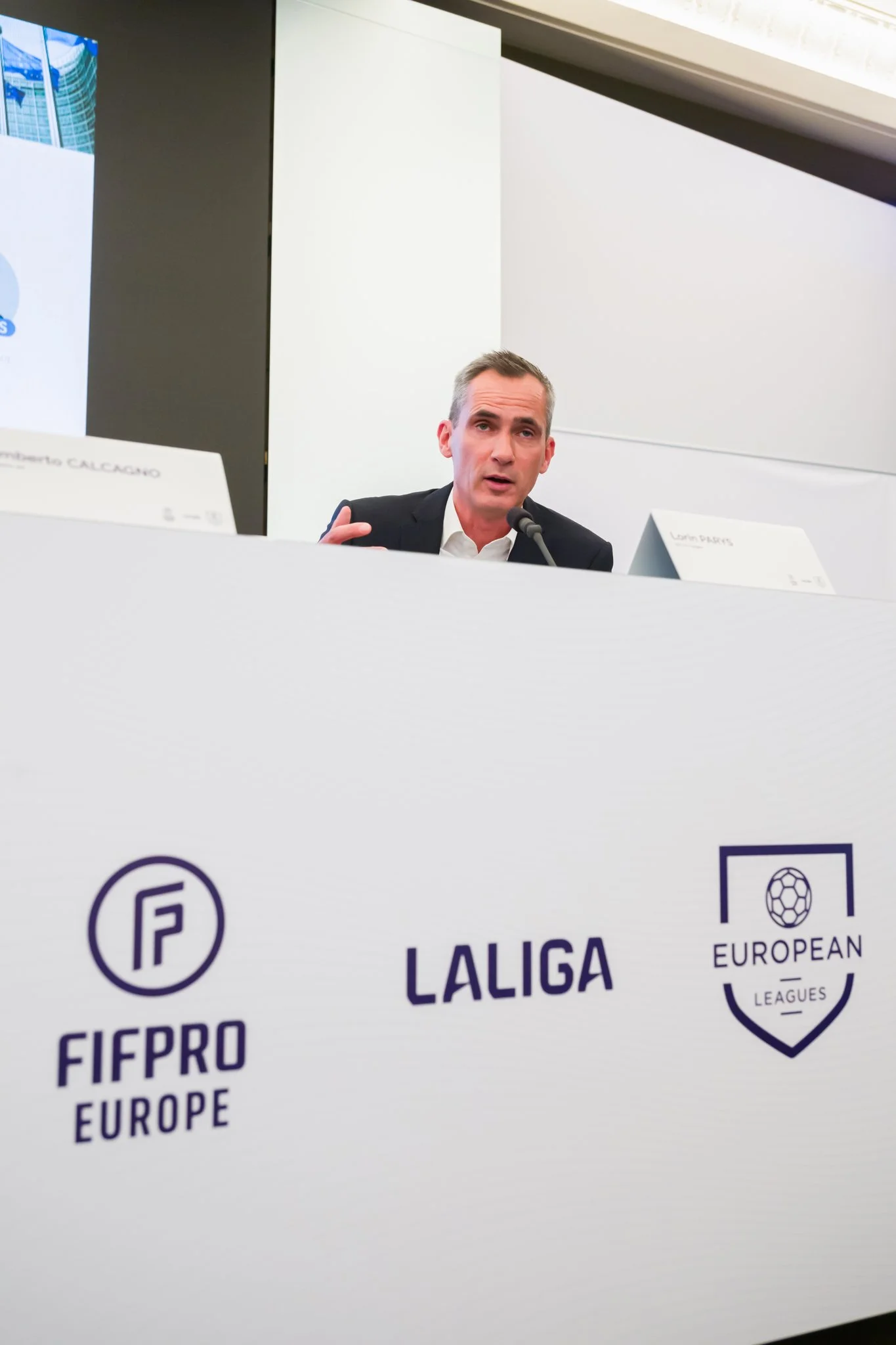 Photographie professionnelle de la conférence de presse de LALIGA. Un homme parlant lors d'une conférence, avec les logos de FIFPRO Europe, LaLiga, et European Leagues visibles sur un panneau.