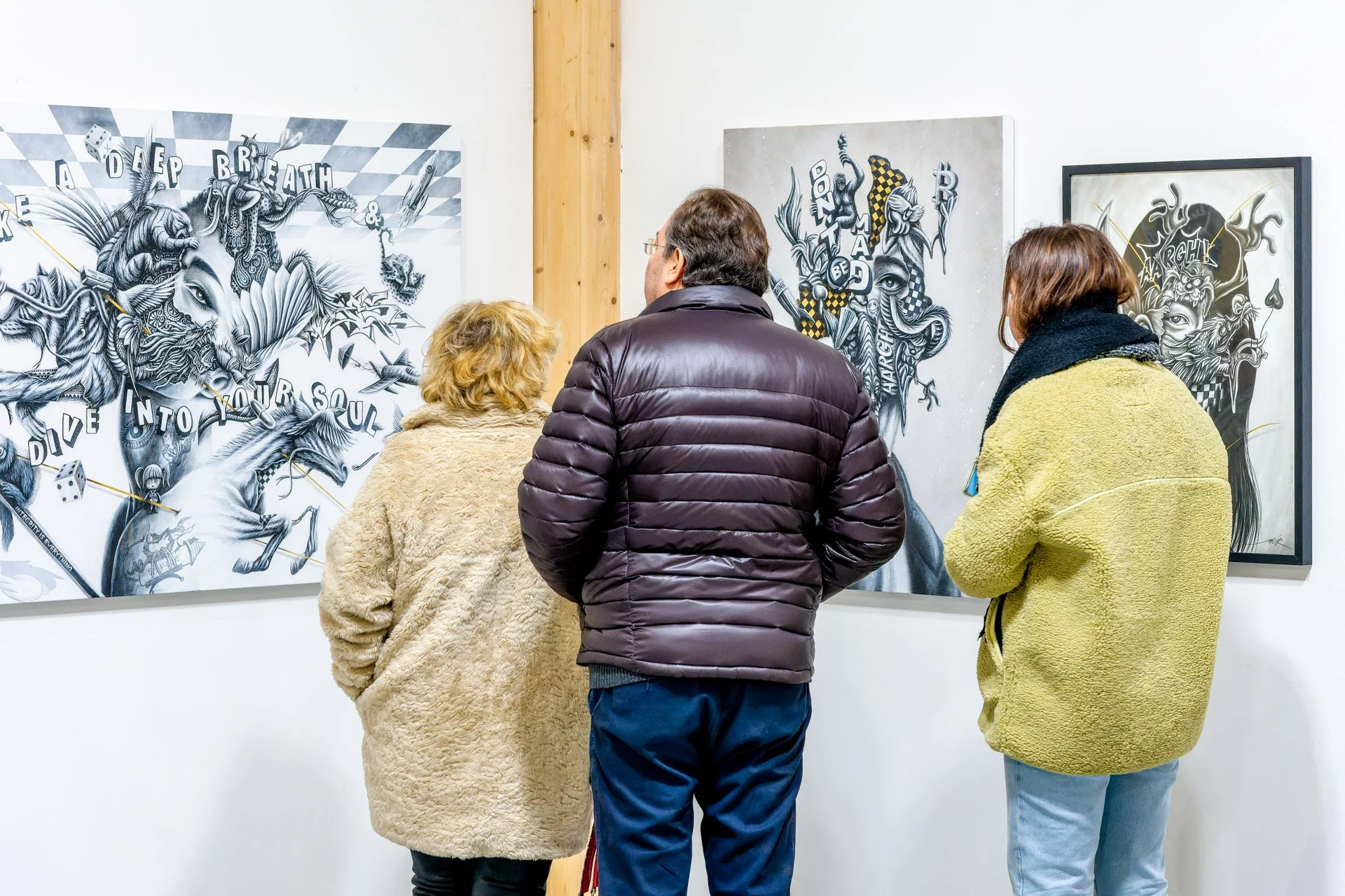 Trois personnes regardent des œuvres d'art contemporain dans une galerie.