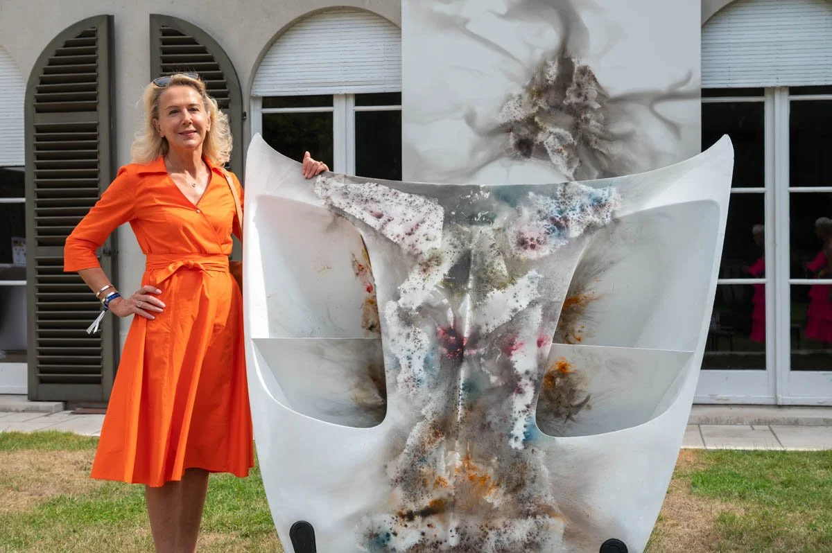 Femme en robe orange près d'une œuvre d'art abstraite.