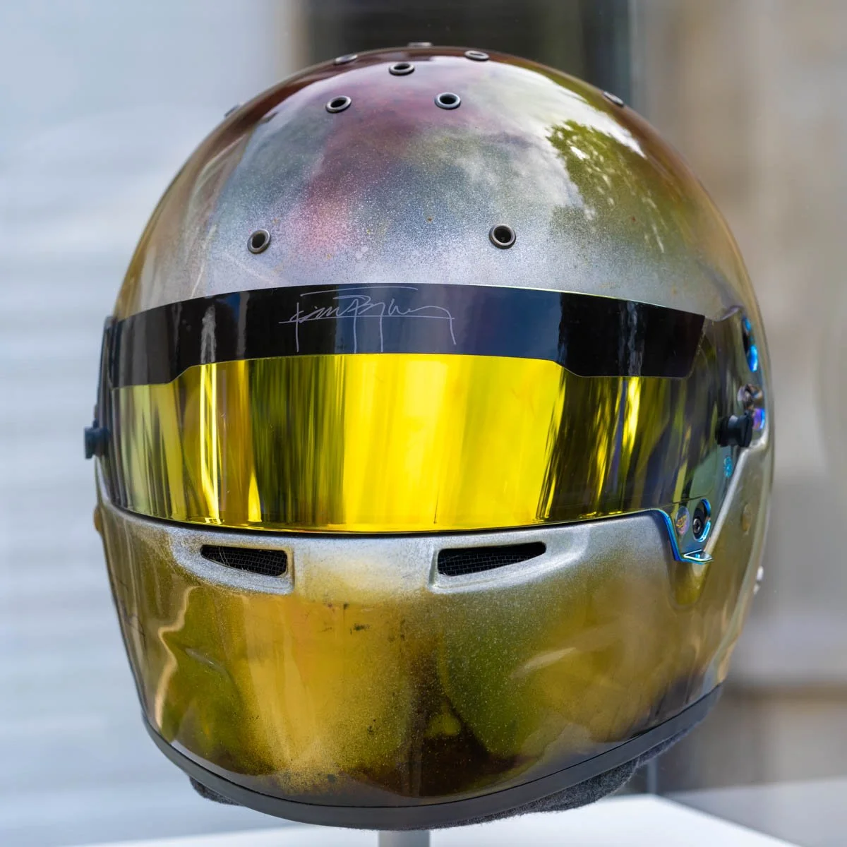 Casque de course avec visière jaune réfléchissante, posé sur un support.