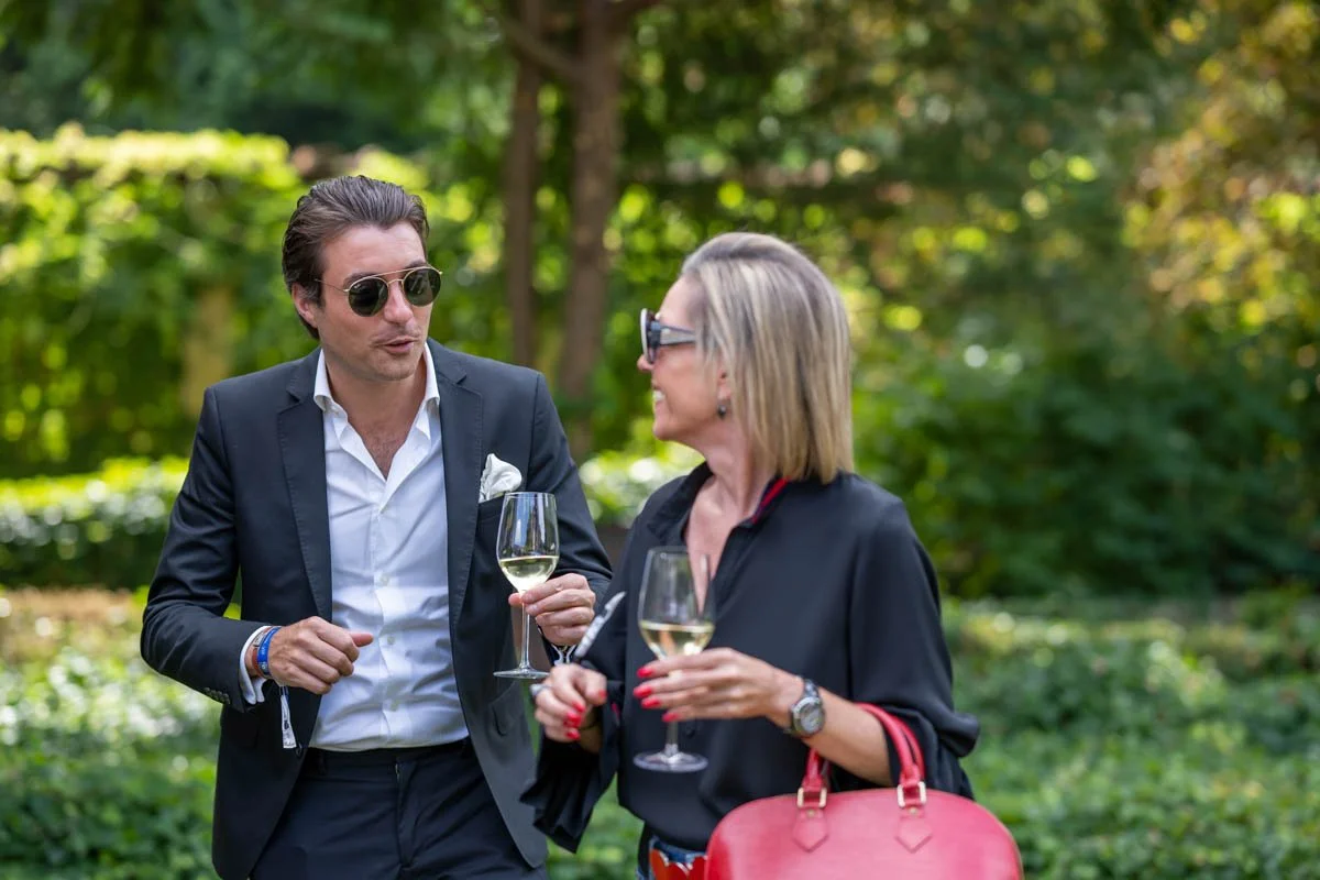 Deux personnes discutent en plein air avec des verres de vin blanc.