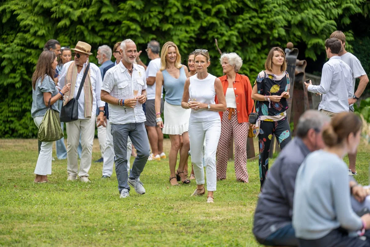 Des personnes marchent et discutent dans un jardin lors d'un événement en plein air.