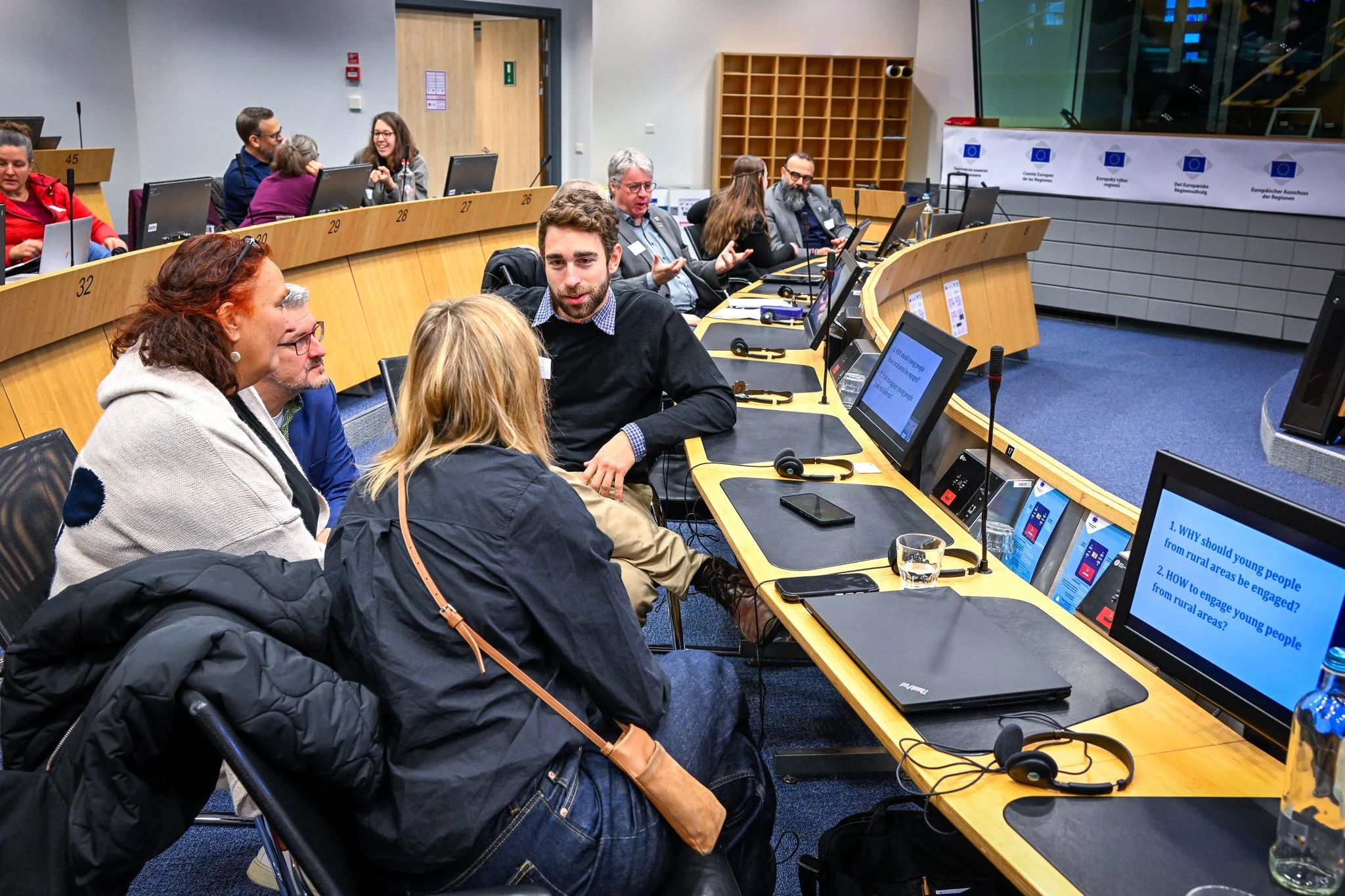Réunion de groupe dans une salle de conférence avec des ordinateurs portables et des micros.