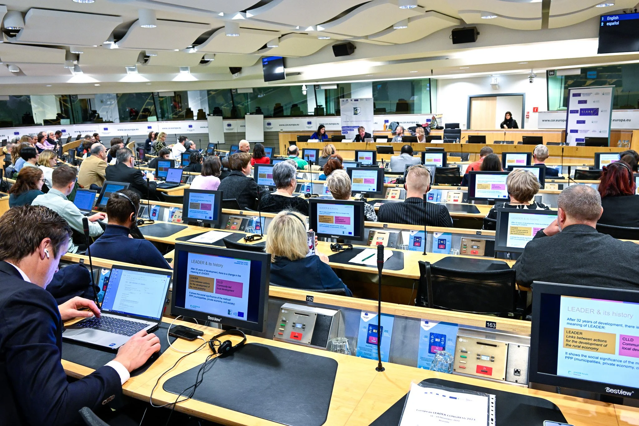 Réunion dans une salle de conférence avec des participants utilisant des ordinateurs et des écrans.