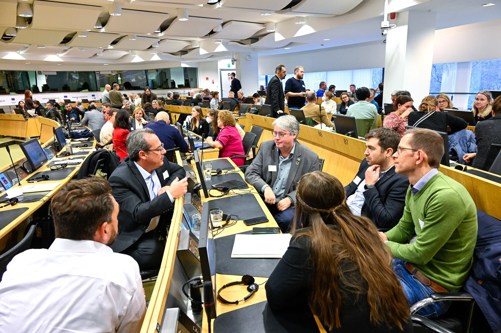 Photo d'une conférence dans le quartier européen à Bruxelles. Groupe de personnes discutant dans une salle de conférence moderne, avec des ordinateurs devant eux.