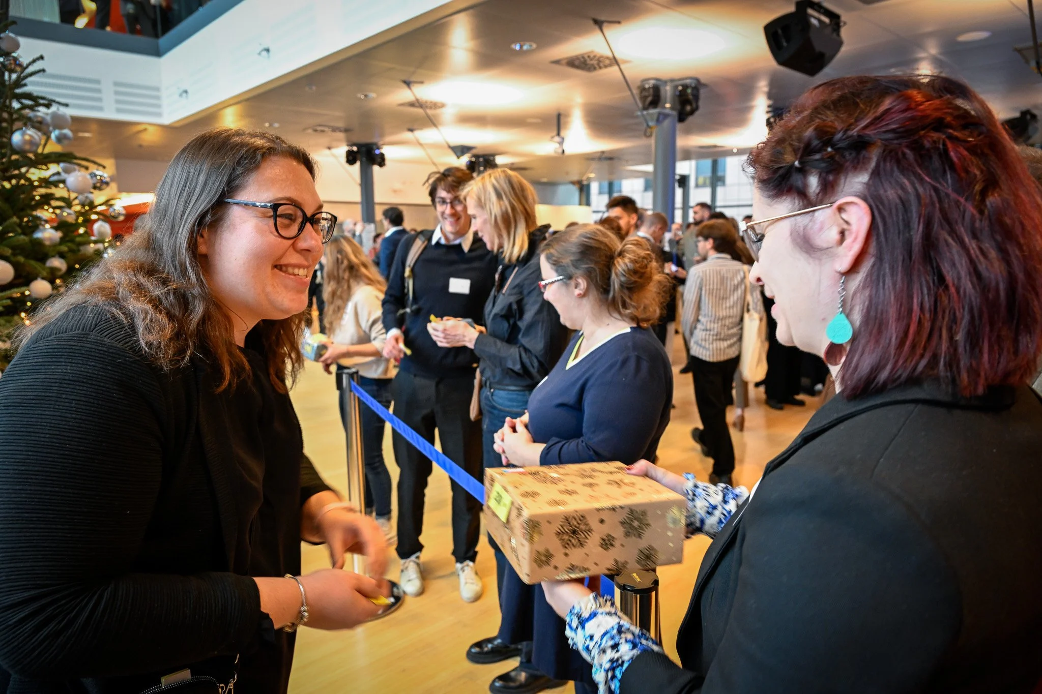 Groupe de personnes discutant et échangeant un cadeau lors d'un événement.