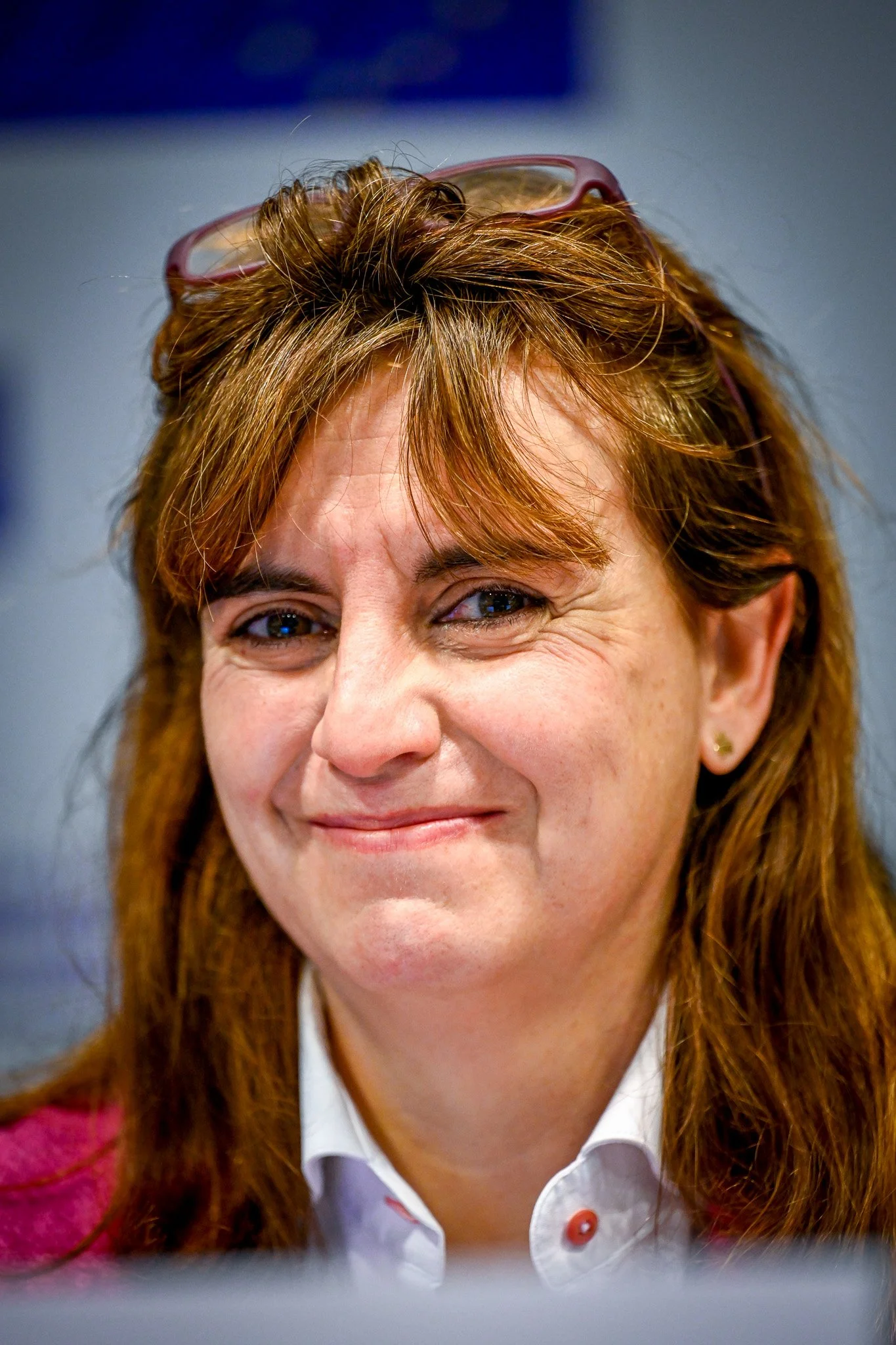 Femme souriante avec des lunettes posées sur la tête.