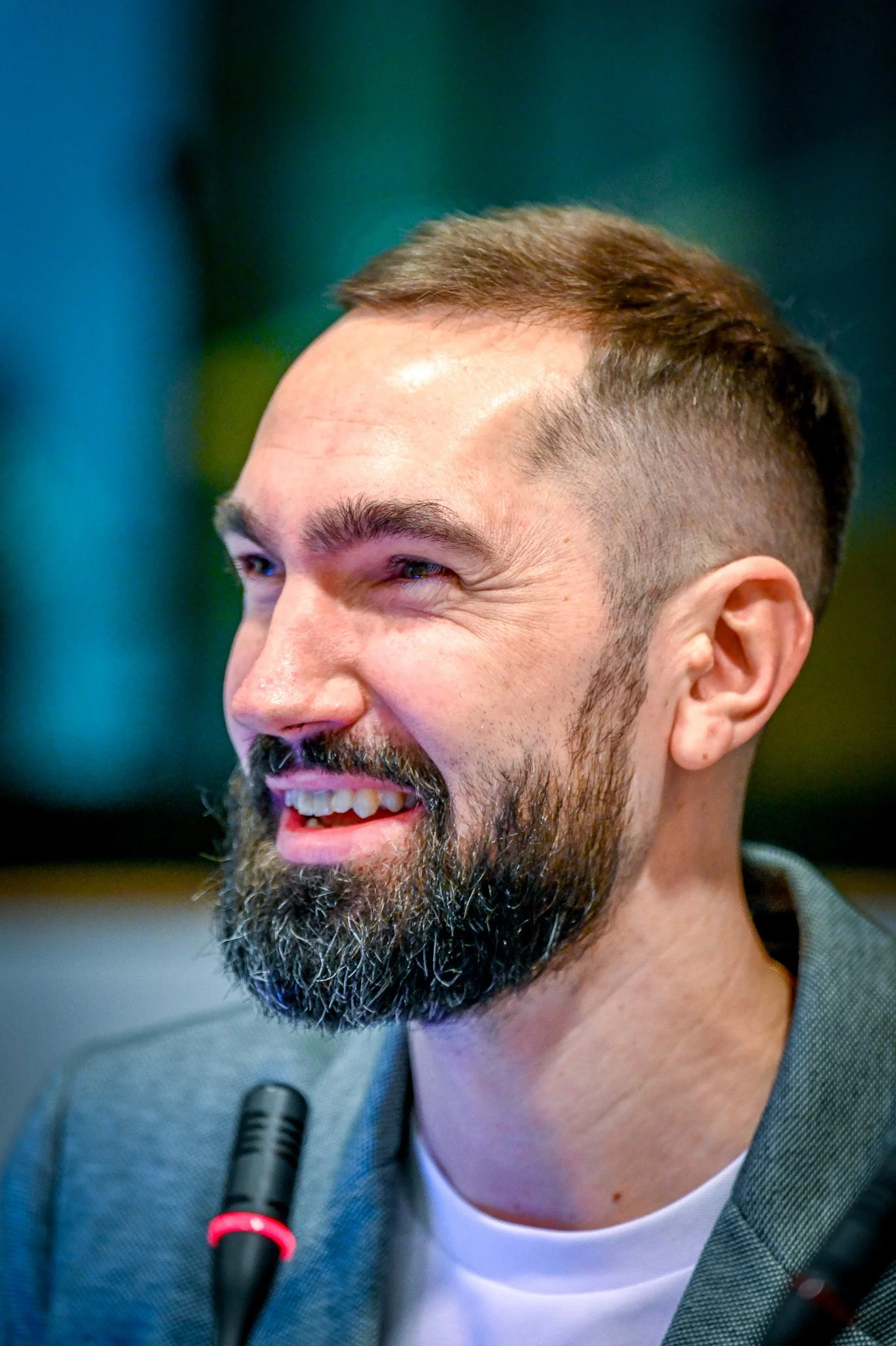 Homme barbu souriant avec un micro.