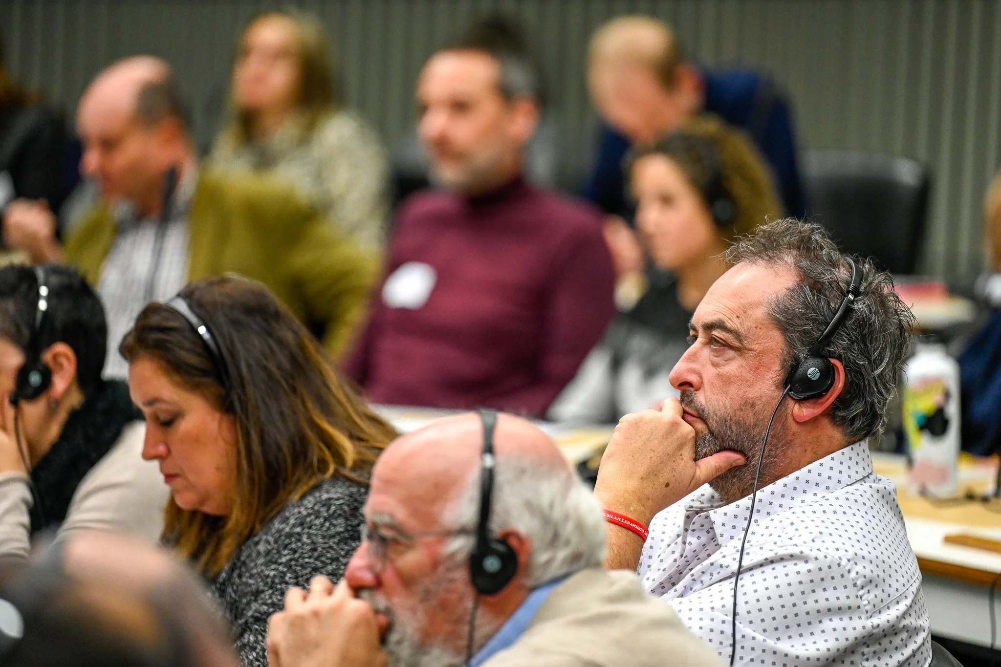 Des personnes assises lors d'une conférence, portant des écouteurs pour la traduction simultanée.