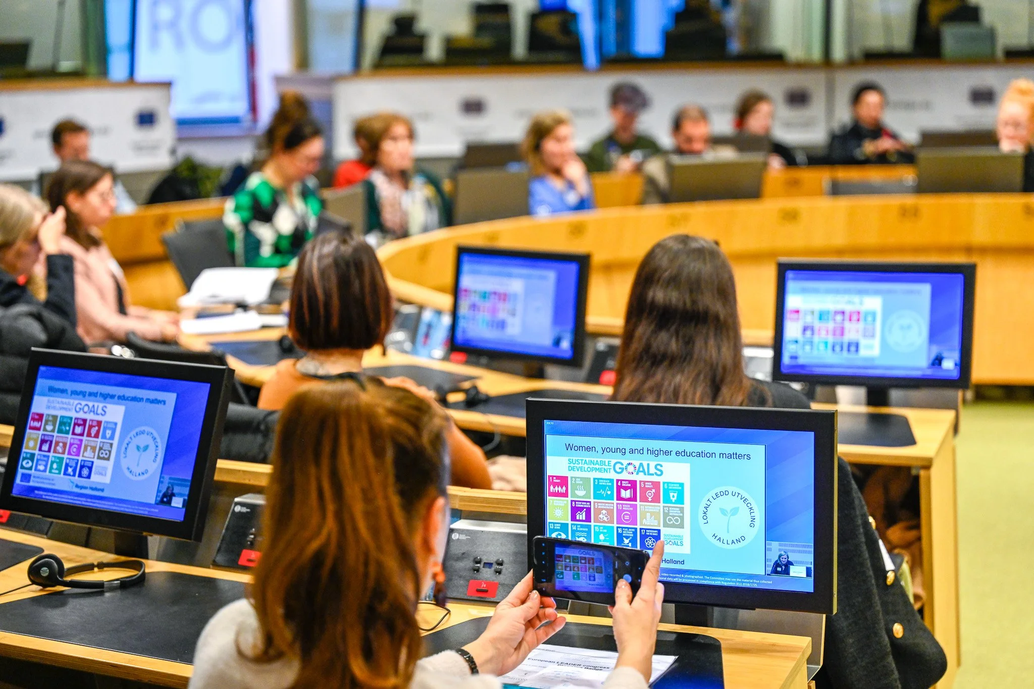 Personnes lors d'une réunion, avec plusieurs écrans affichant les objectifs de développement durable de l'ONU.