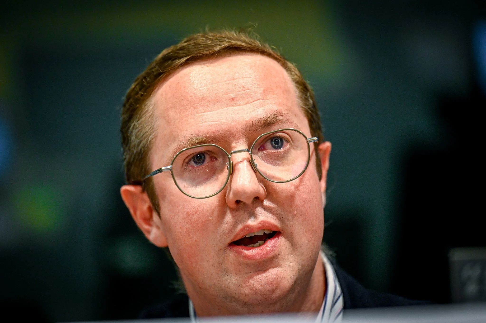 Un homme avec des lunettes parle lors d'un événement.