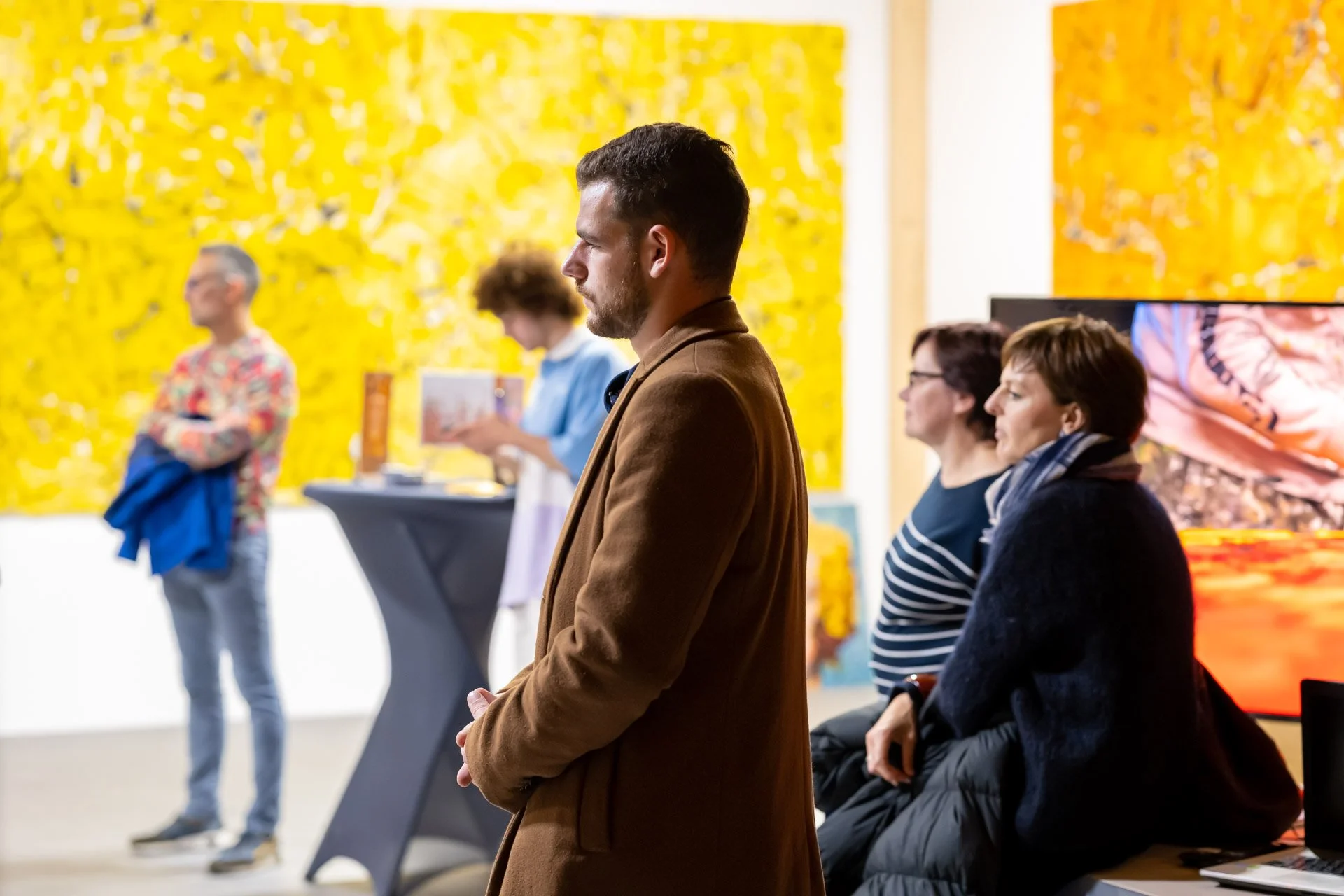 People chatting in an art gallery, with colourful artworks in the background.