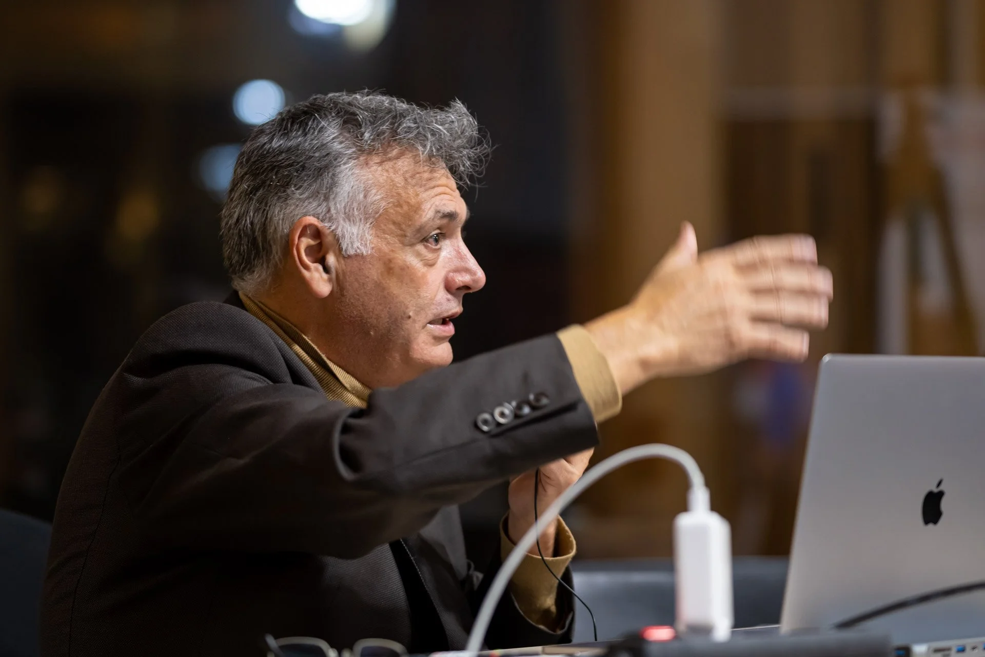 Vincent Parissis, sitting in front of a laptop, accompanies his talk with a hand gesture at the ART NFT Gallery.