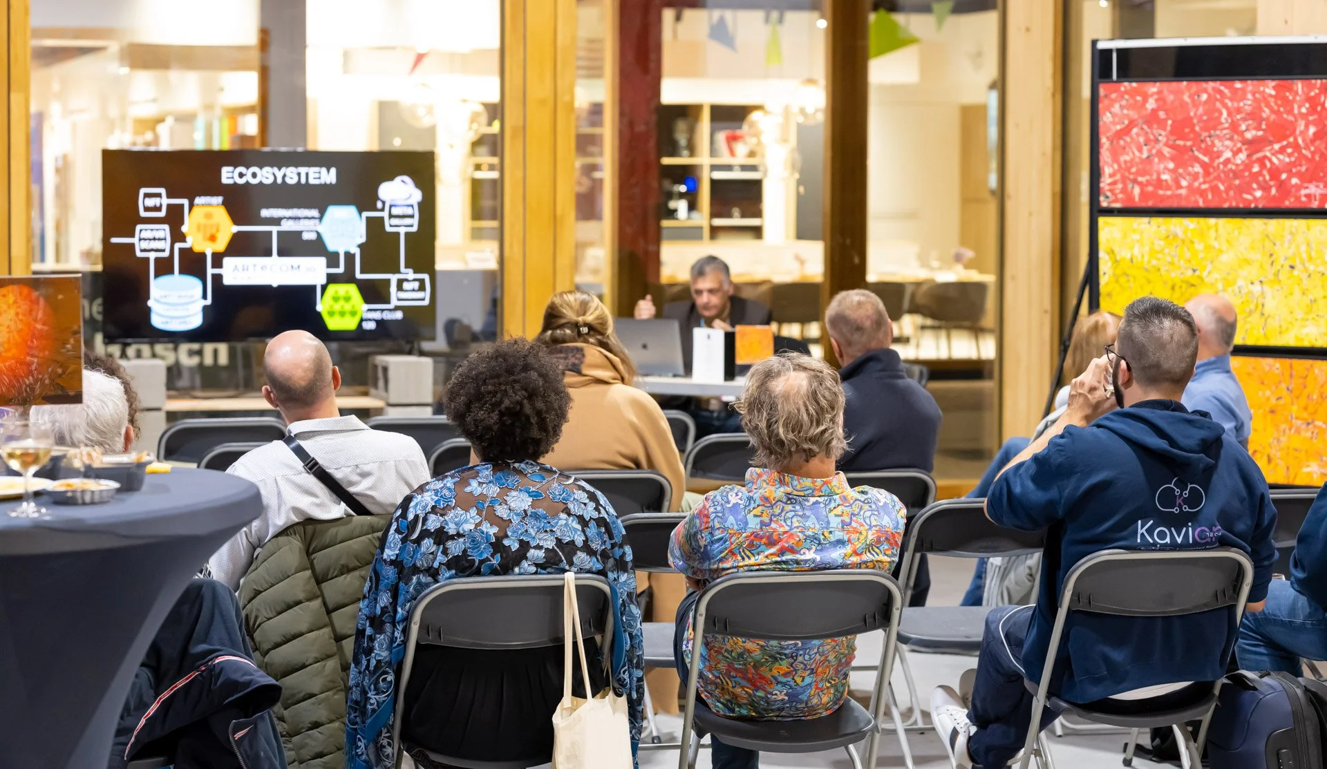 People sitting during a presentation, with a screen displaying a diagram entitled ‘Ecosystem’.