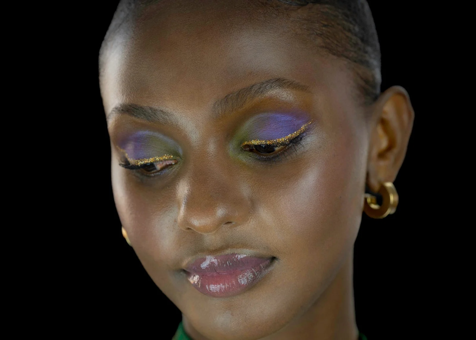 Femme avec maquillage coloré et boucles d'oreilles dorées