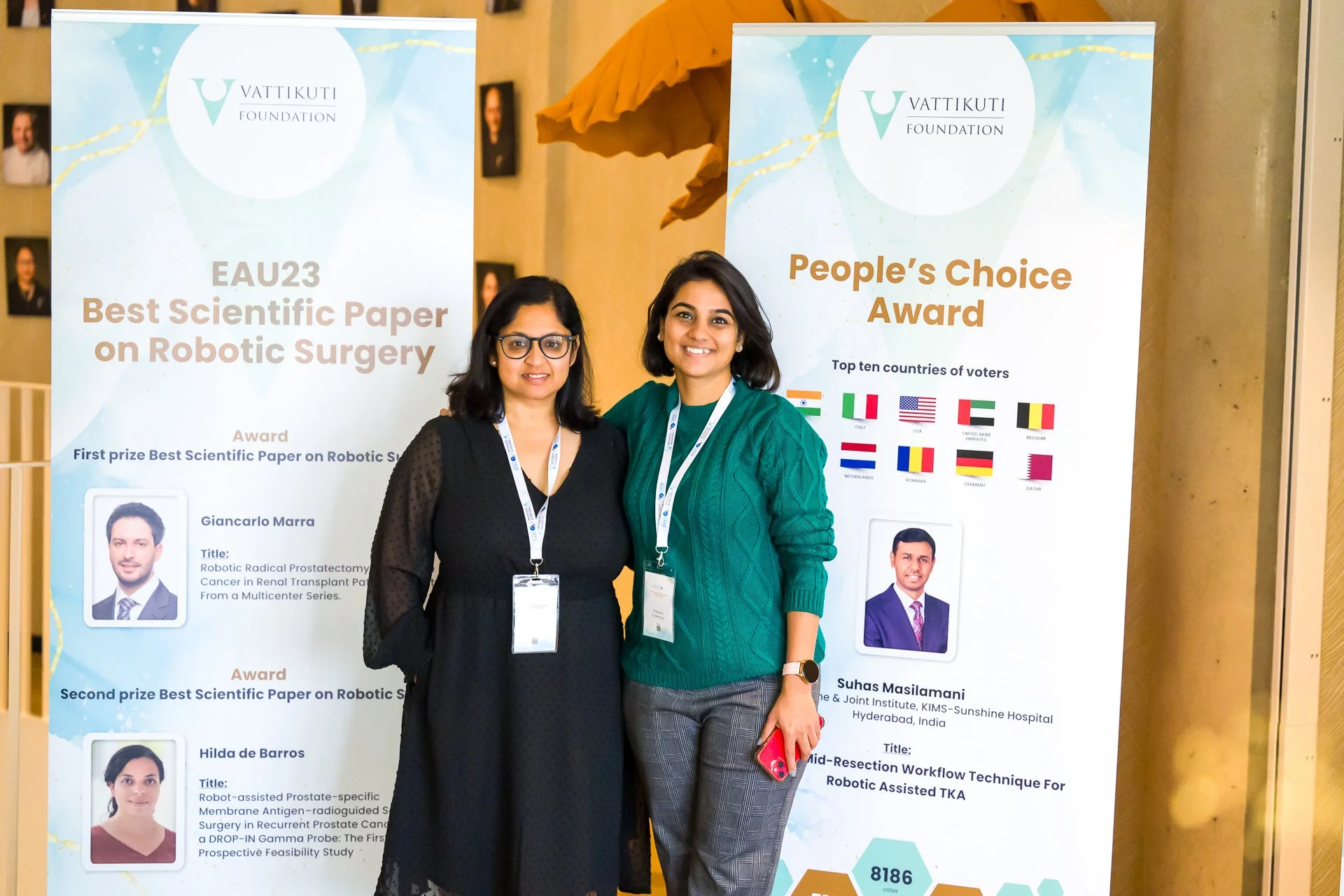 Photographie professionnelle d'une conférence médicale. Deux personnes debout devant des panneaux de prix scientifiques décernés pour la chirurgie robotique par la Vattikuti Foundation. Les panneaux affichent le « Best Scientific Paper on Robotic Sur
