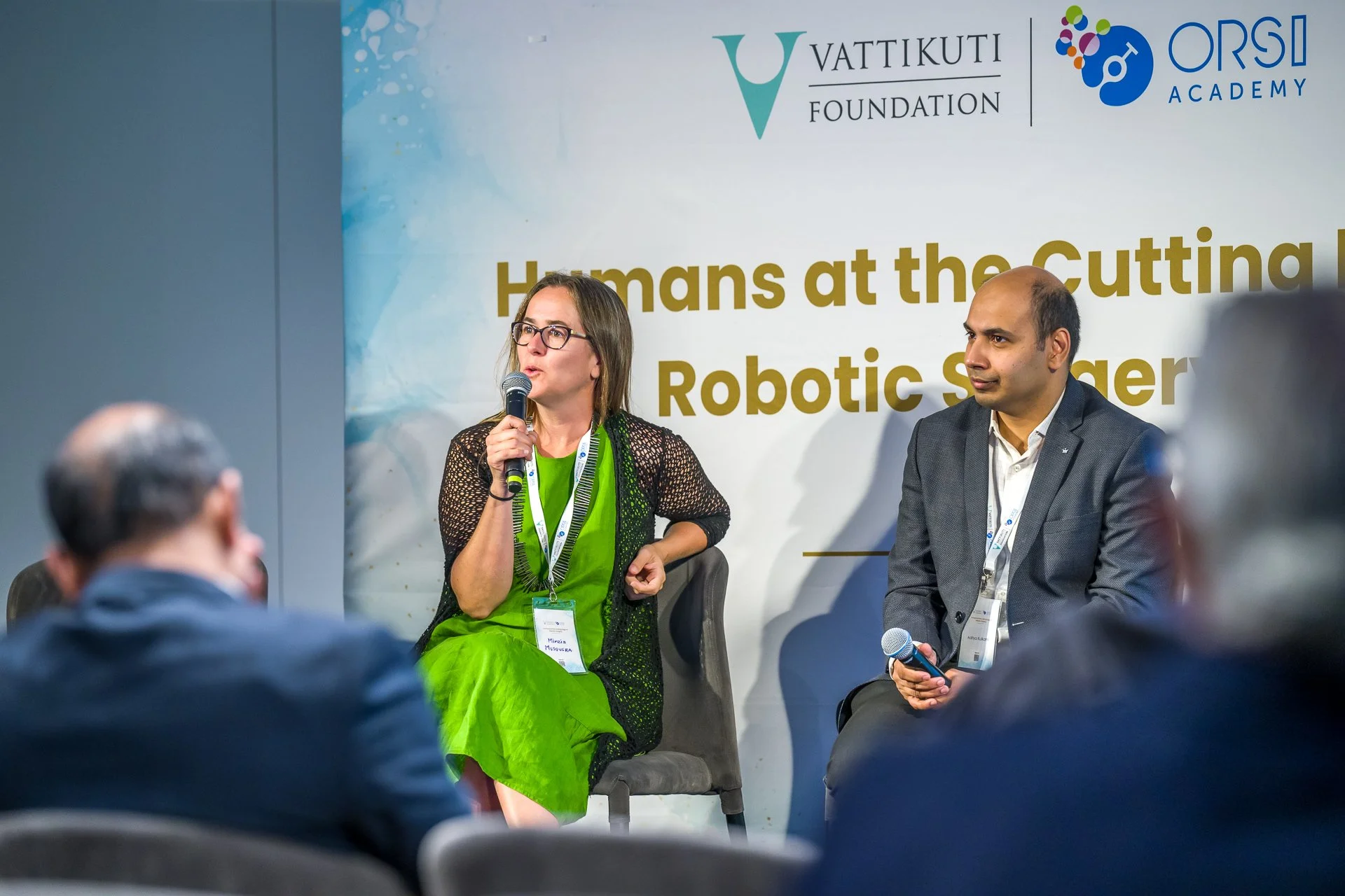 Deux personnes discutent sur scène lors d'une conférence sur la chirurgie robotique, avec les logos de la "Vattikuti Foundation" et "ORSI Academy" en arrière-plan.