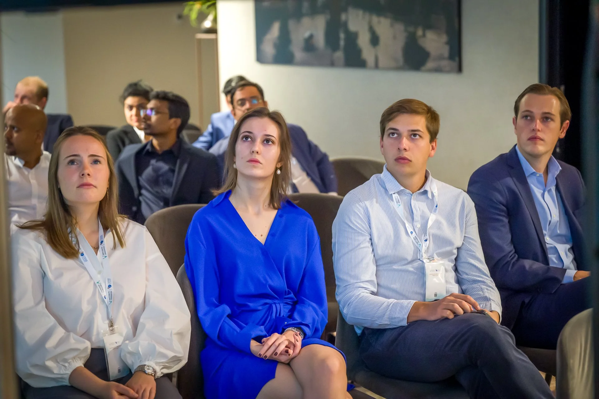 Groupe de personnes assises dans une conférence, attentives en regardant vers l'avant.