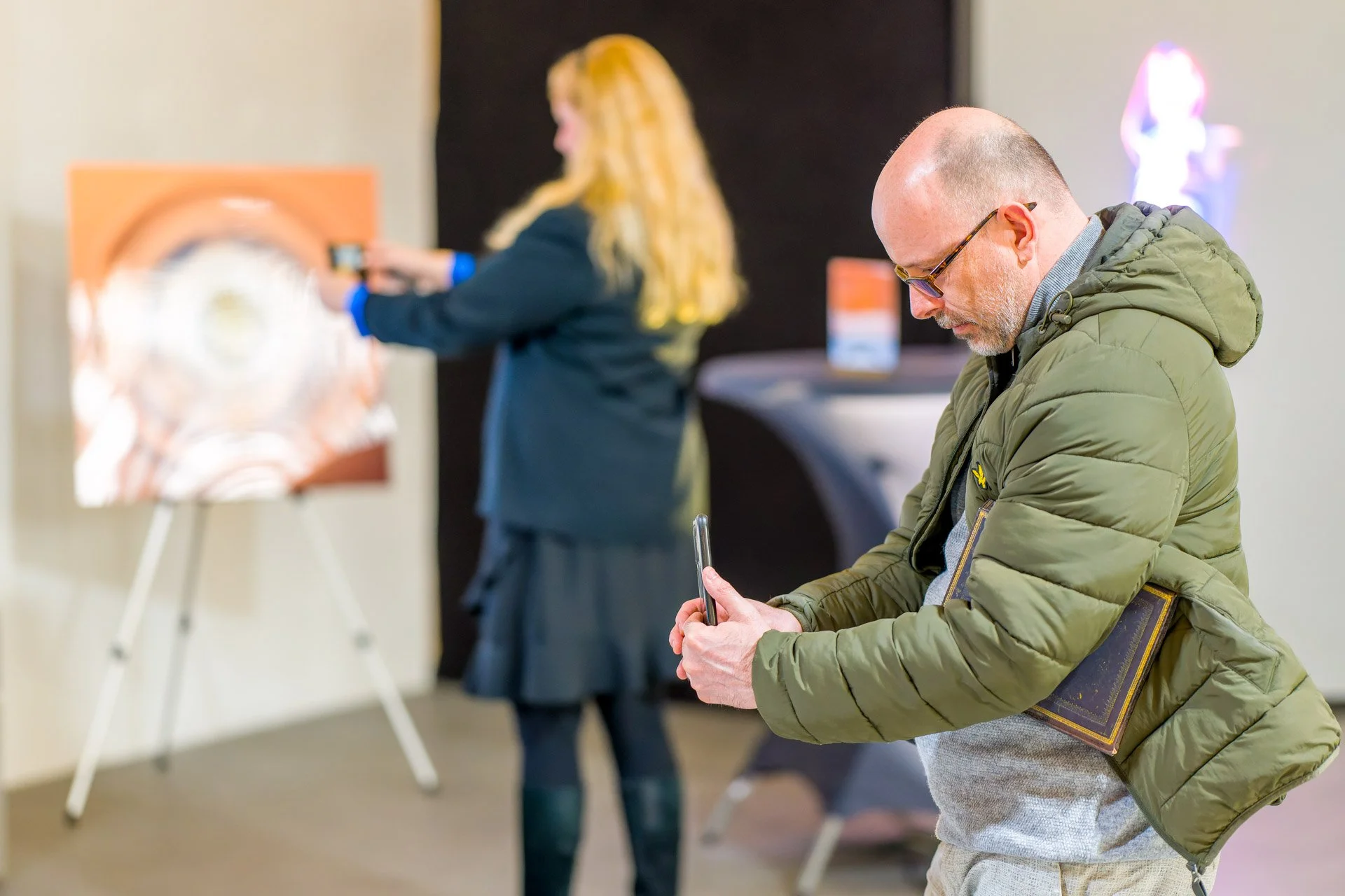 Deux personnes regardant et utilisant leurs téléphones dans une galerie d'art.