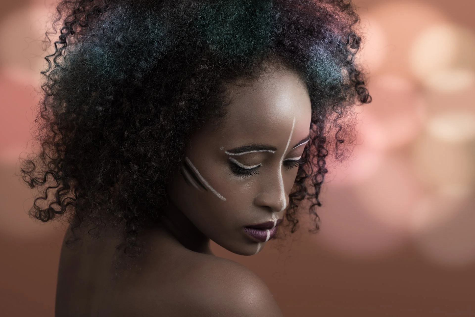 Femme avec maquillage artistique, cheveux bouclés et fond flou.