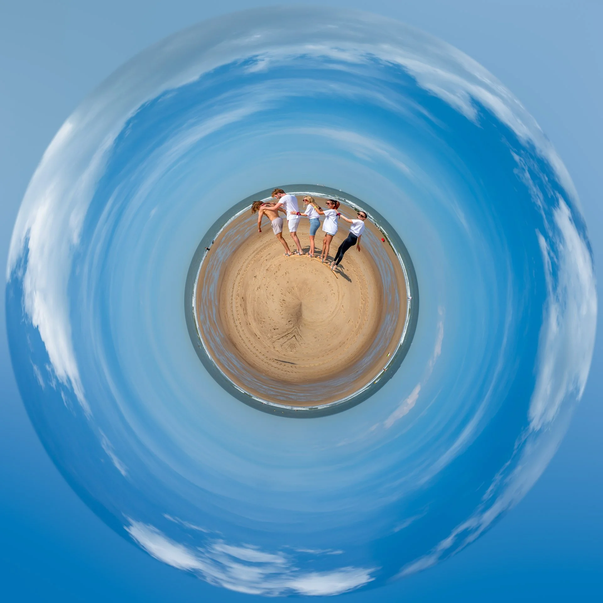 A miniature view of a beach with a group of participants in the centre, surrounded by the sea and the blue sky.