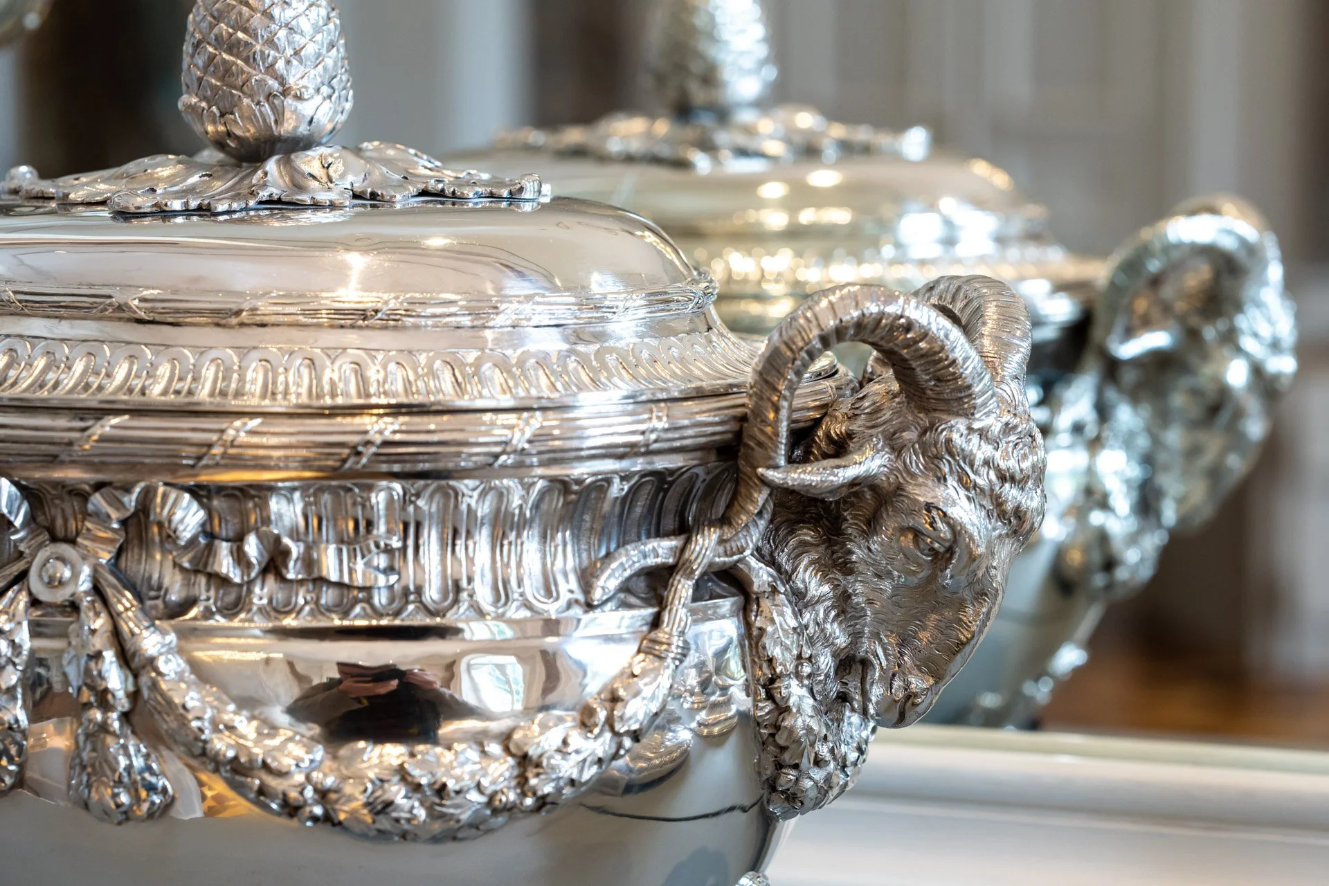 Gros plan sur une soupière en argent richement ornée, exposée au château de Seneffe.