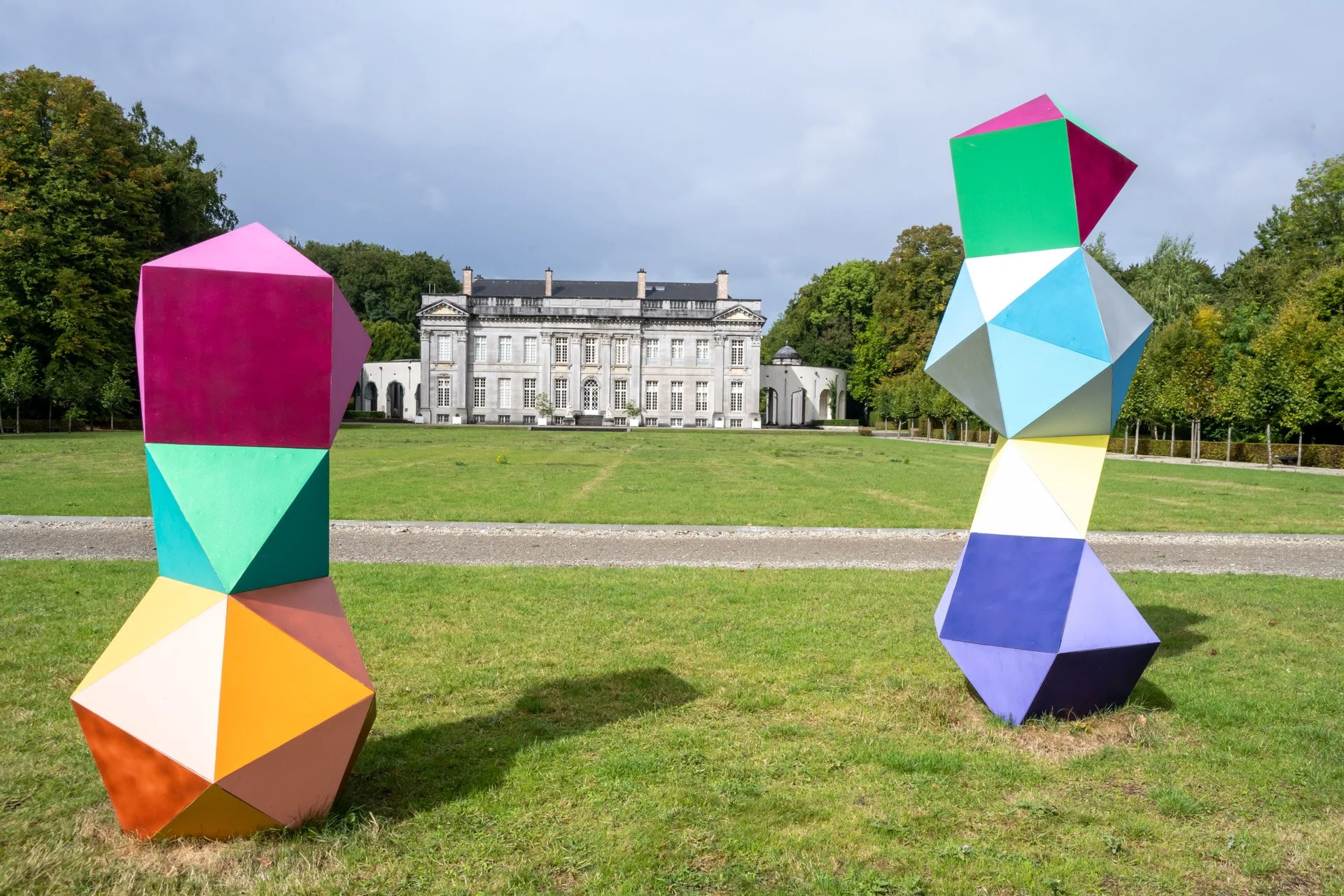 Deux sculptures géométriques multicolores dans le parc du château de Seneffe, avec le château à l’arrière-plan.