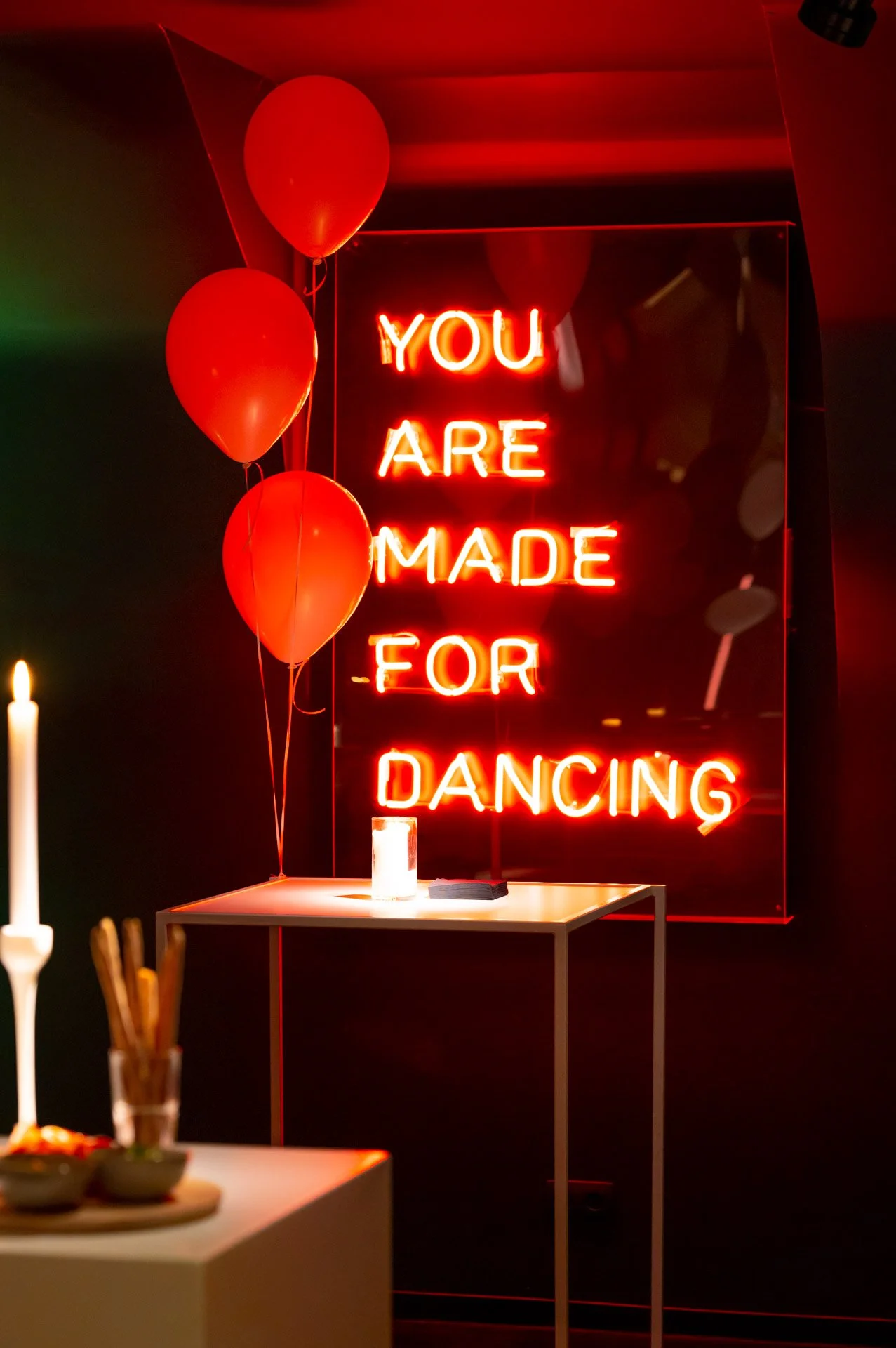 An illuminated sign reading ‘You are made for dancing’ in a space lit up in red and decorated with balloons at the Calypso in Knokke.