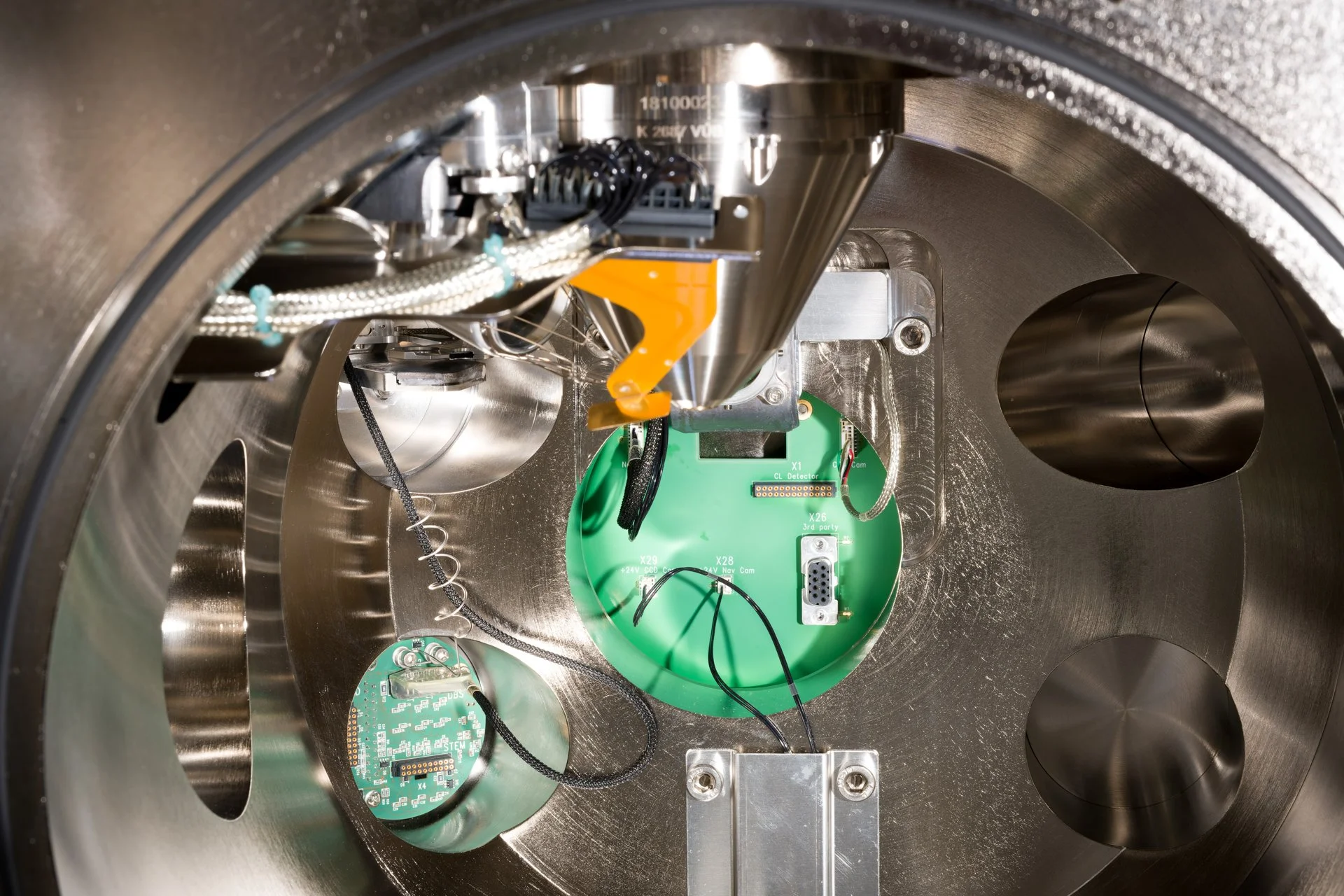 The interior of a vacuum chamber containing electronic components and connected cables.