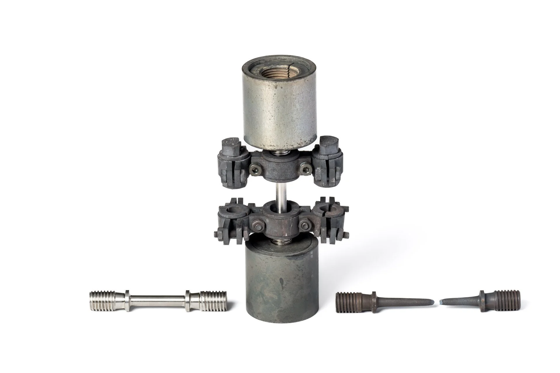 A mechanical component consisting of two metal cylinders, assembled using gears and bolts, accompanied by two smaller threaded metal parts, set against a white background.