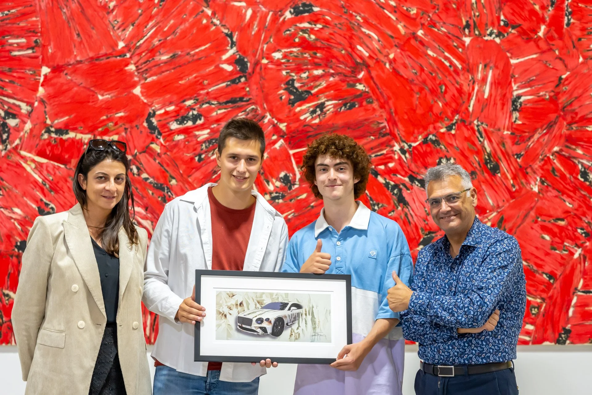 Four participants pose with a framed artwork in front of a large red painting during the opening of the BXL ART NFT Gallery.
