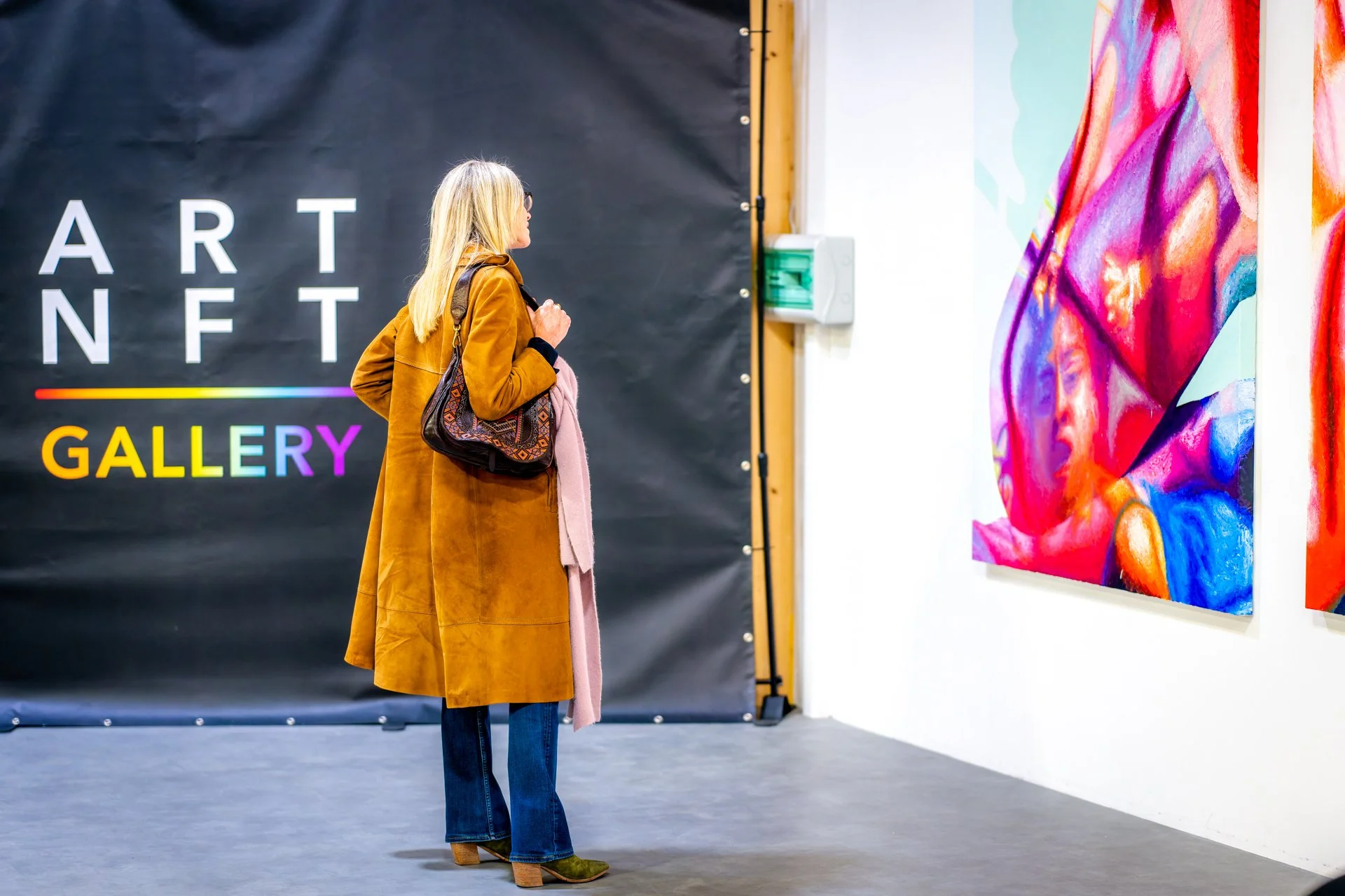 Une femme regarde des œuvres d'art colorées dans une galerie d'art NFT.